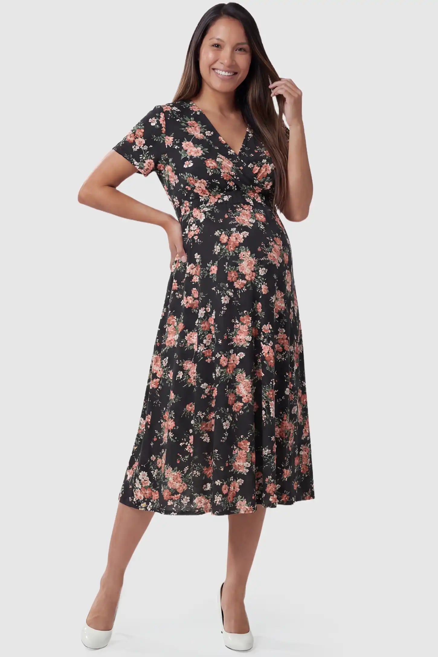 Smocked Waist Crossover Maternity Midi Dress in black floral print featuring V-neck wrap bodice and A-line midi skirt on pregnant model. front view