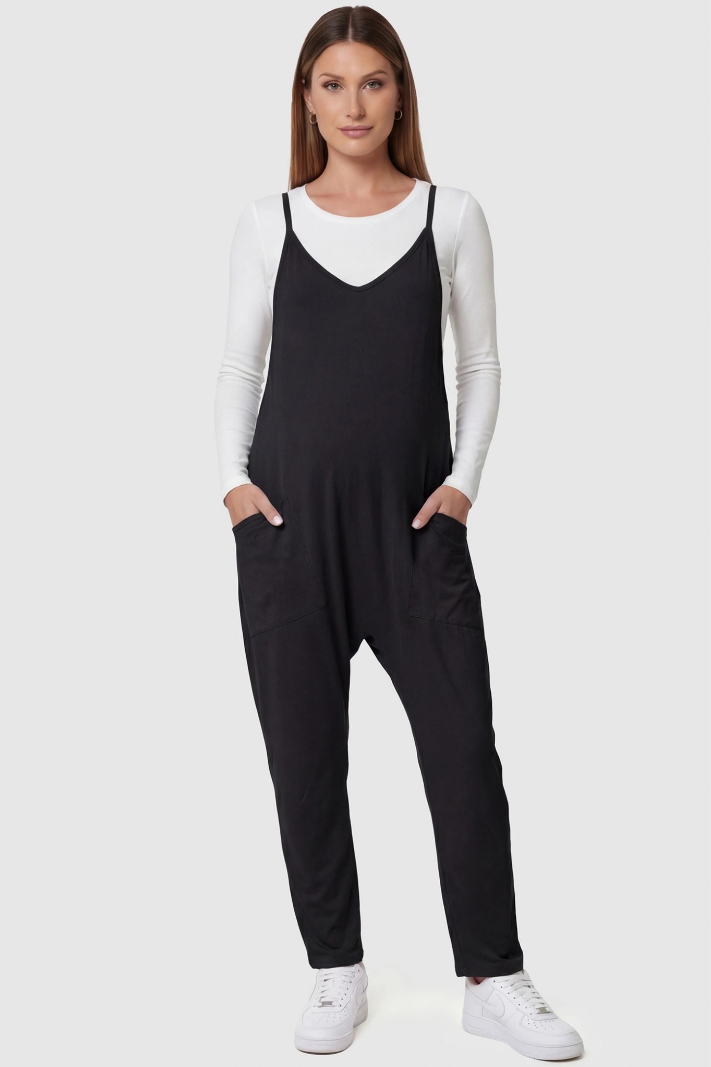 Adjustable Strap Relaxed Maternity Jumpsuit in Black featuring a loose fit and functional pockets on a pregnant model.