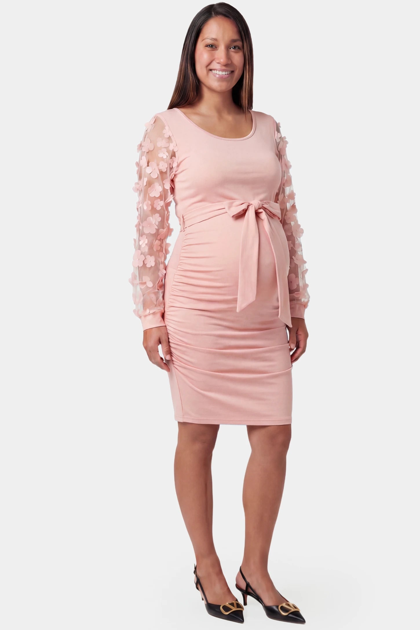 Sheer long-sleeve tie-waist short maternity dress in pink featuring waist sash in front view on a pregnant model