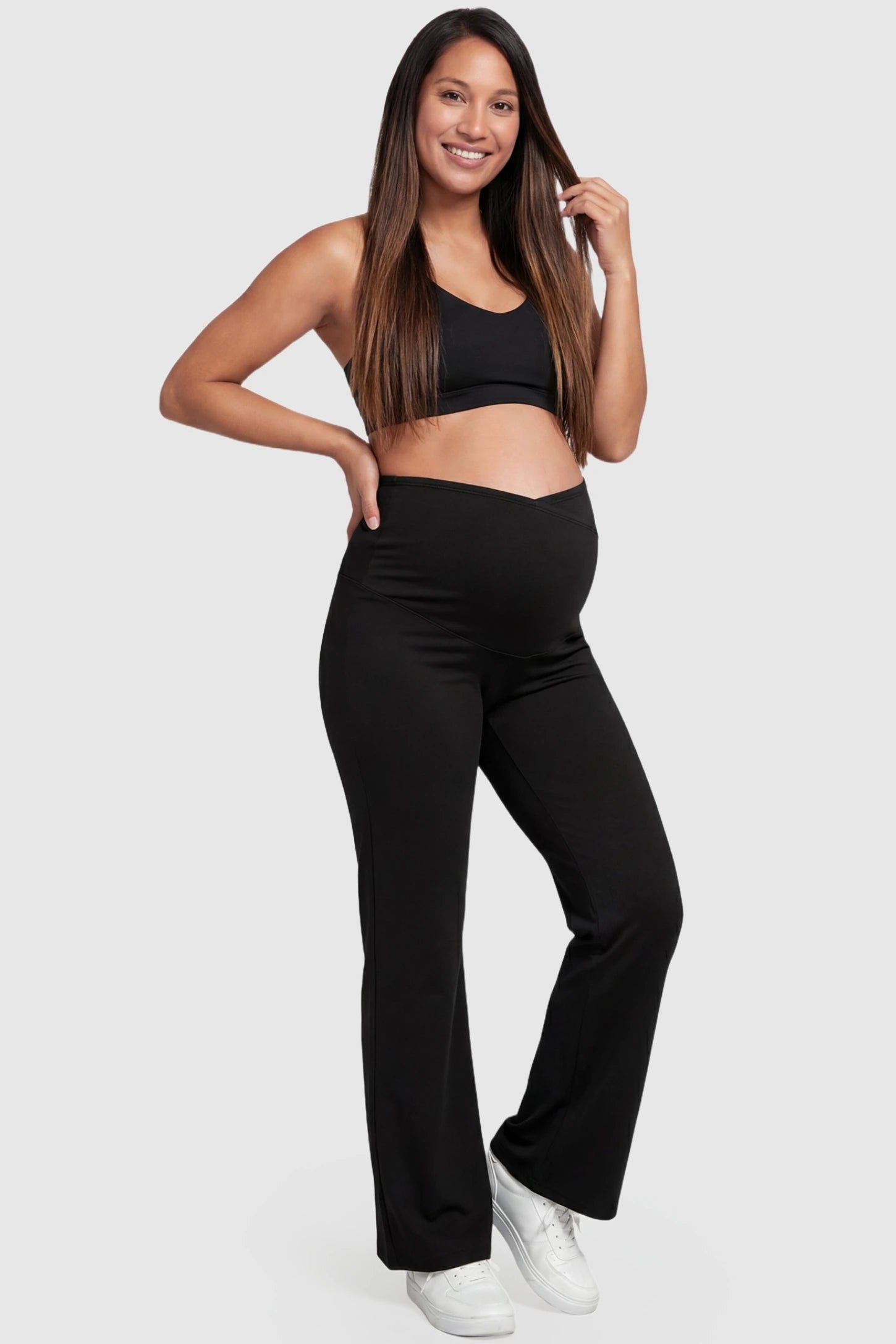Cross Over High-Waisted Wide-Leg Maternity Pants in Black with a versatile cross-front design on a pregnant in full body shot.model.
