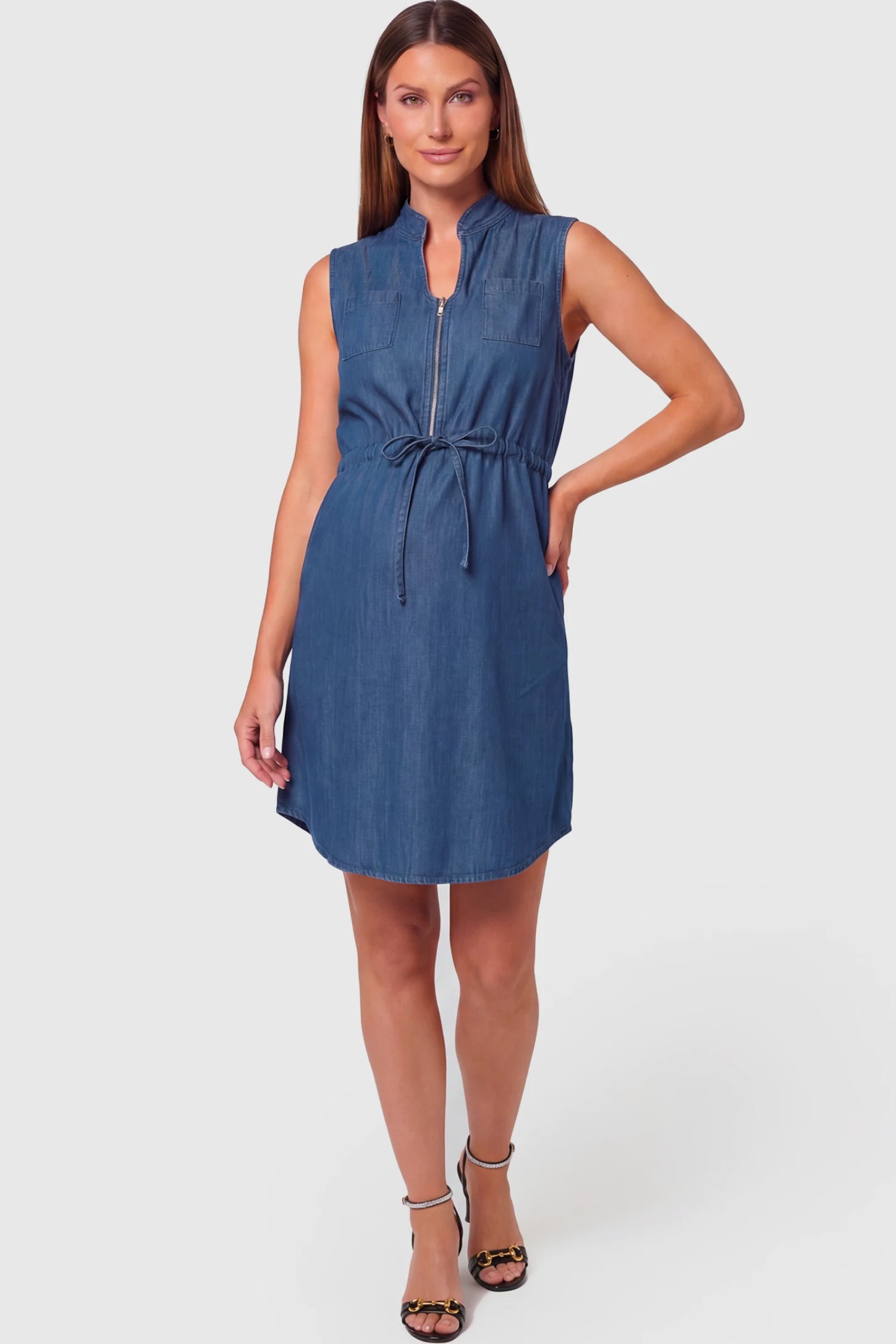 Denim Sleeveless Maternity & Nursing Midi Shirt Dress in dark blue featuring front zipper, stand collar, and adjustable drawstring waist on a pregnant model.