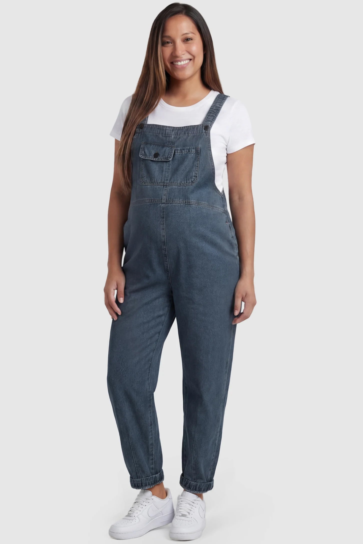 Wide Leg Denim Maternity Overalls in blue with adjustable straps and relaxed fit on pregnant model front view.
