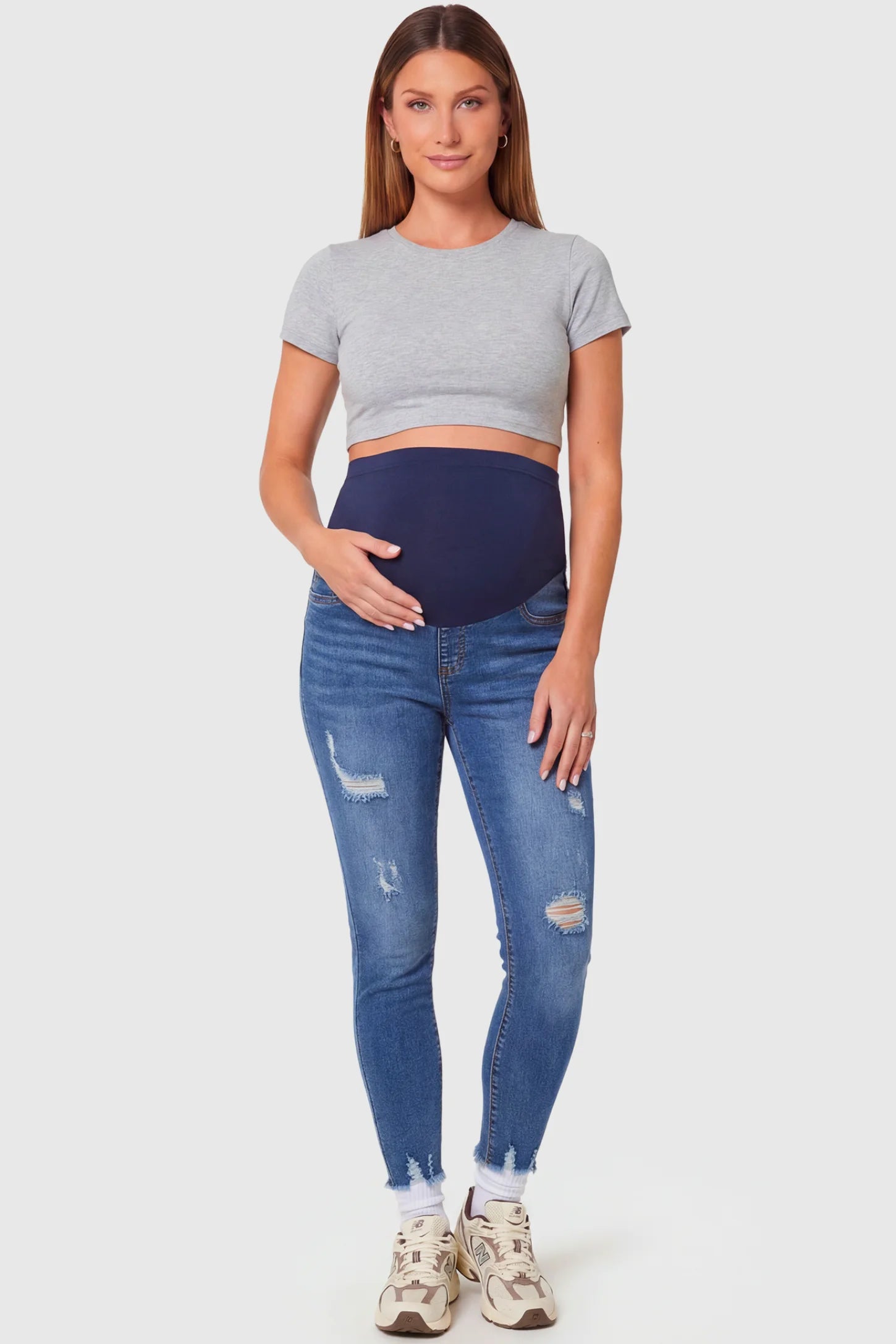 High-Rise Distressed Skinny Maternity Jeans in navy blue featuring over-the-belly support panel and frayed hem on a pregnant model.