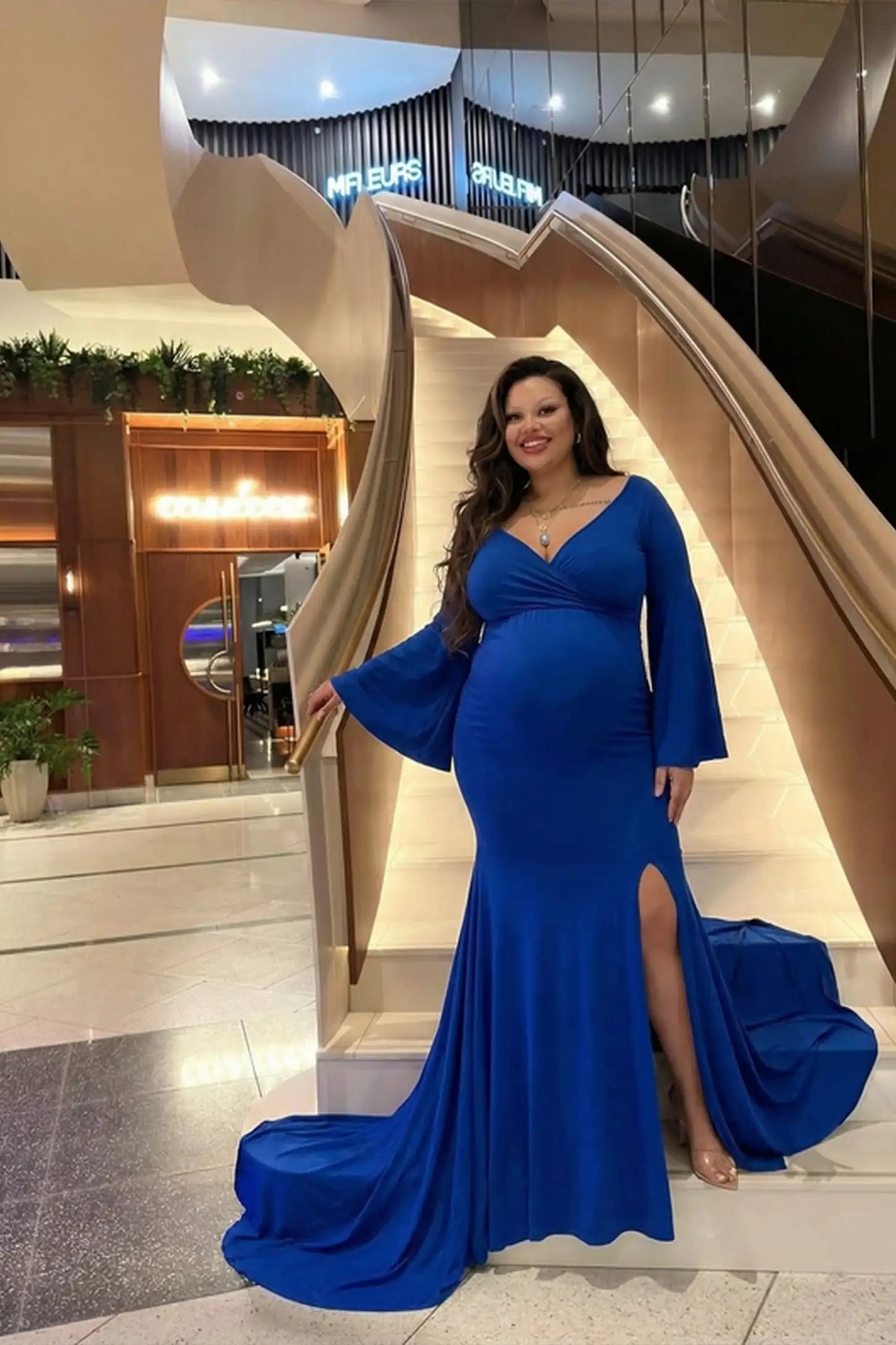 Blue Wrap Flared Fishtail Maternity Gown featuring long bell sleeves on a pregnant model in a front view.