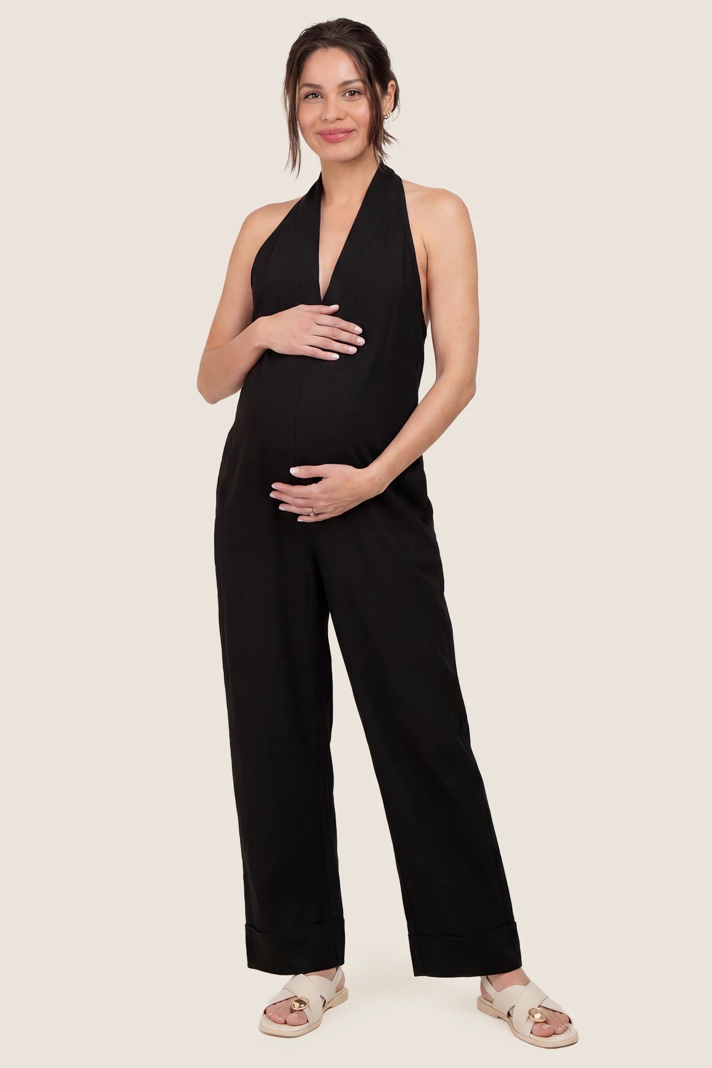 Halter neck wide-leg maternity jumpsuit in black with chic halter neckline, front view on pregnant model