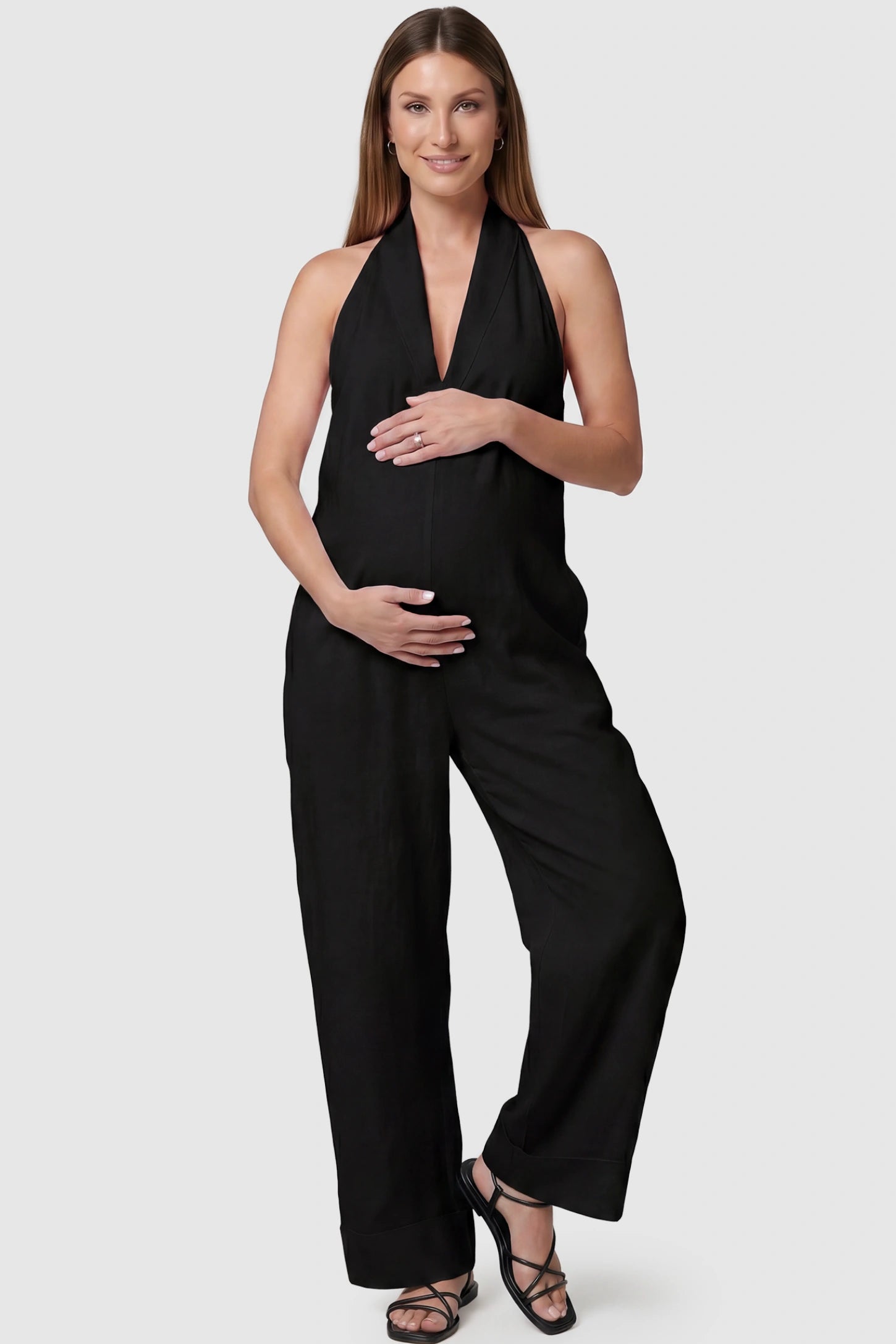 Halter neck wide-leg maternity jumpsuit in black with chic halter neckline, front view on pregnant model