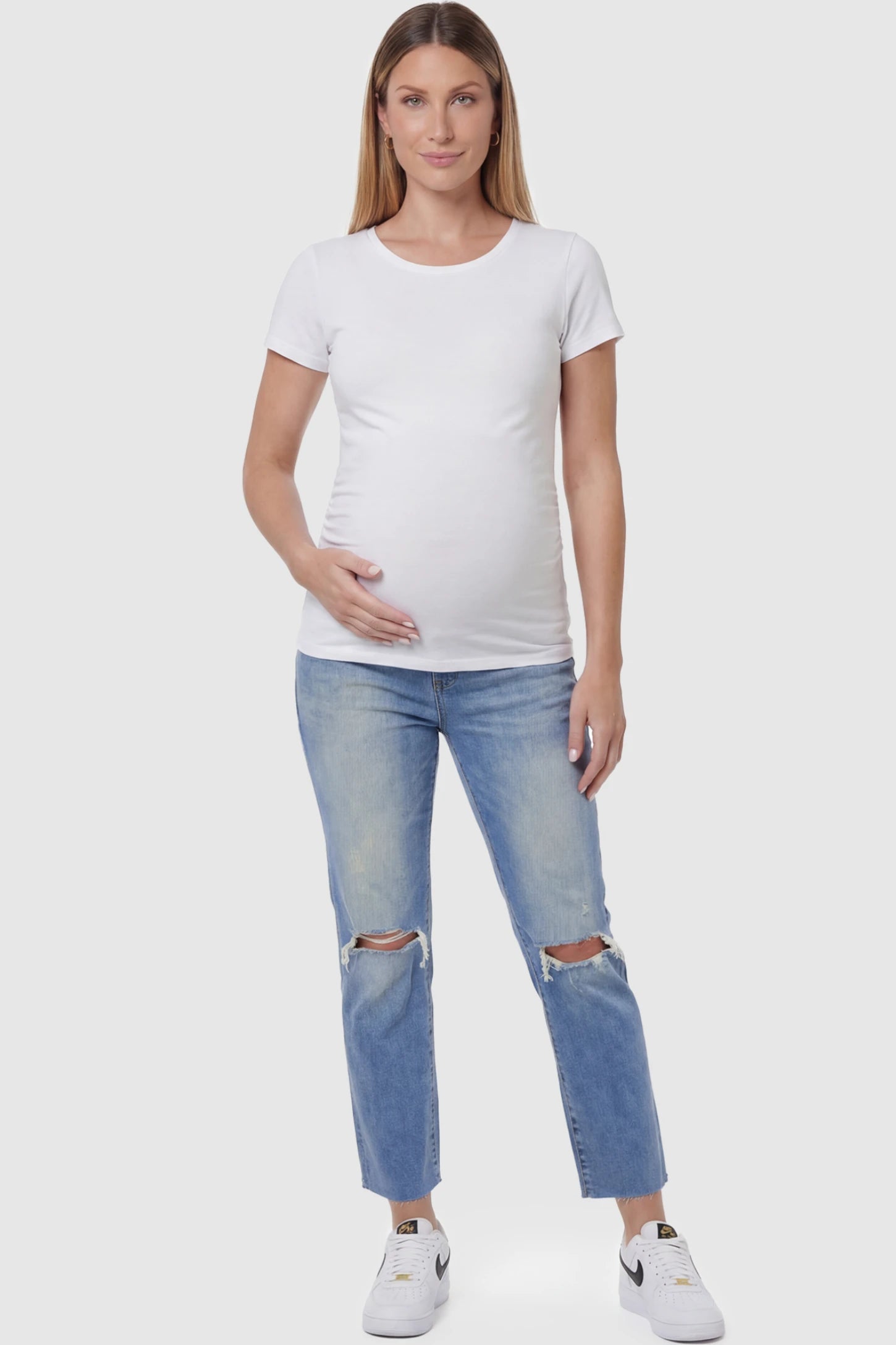 Raw Hem Ankle Straight Leg Maternity Jeans in blue denim featuring high-rise over-the-belly panel and knee-open distressing on pregnant model showing full body.