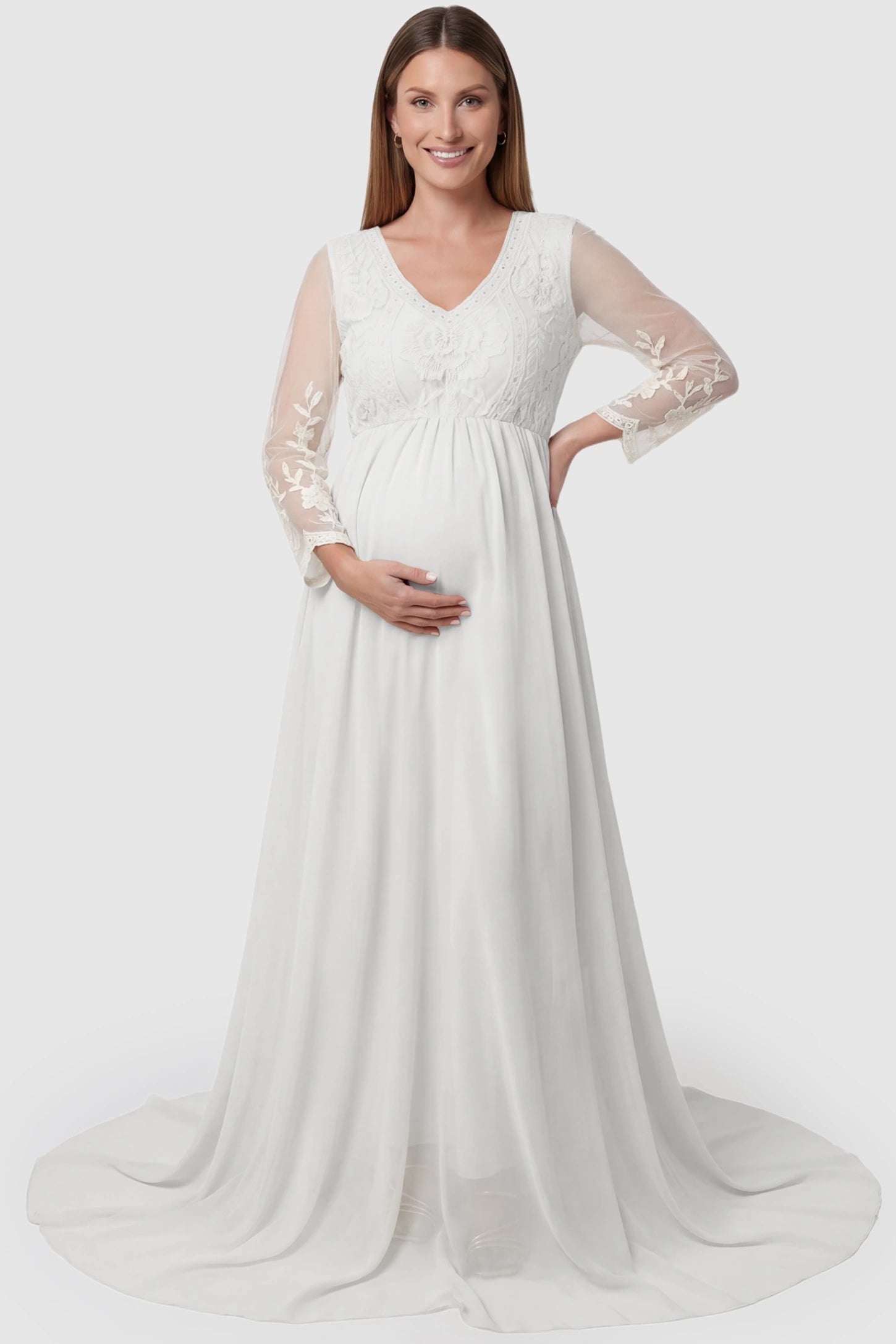 Lace trim long sleeve train maternity gown in white with flowing train silhouette & mesh sleeves, front view on pregnant model
