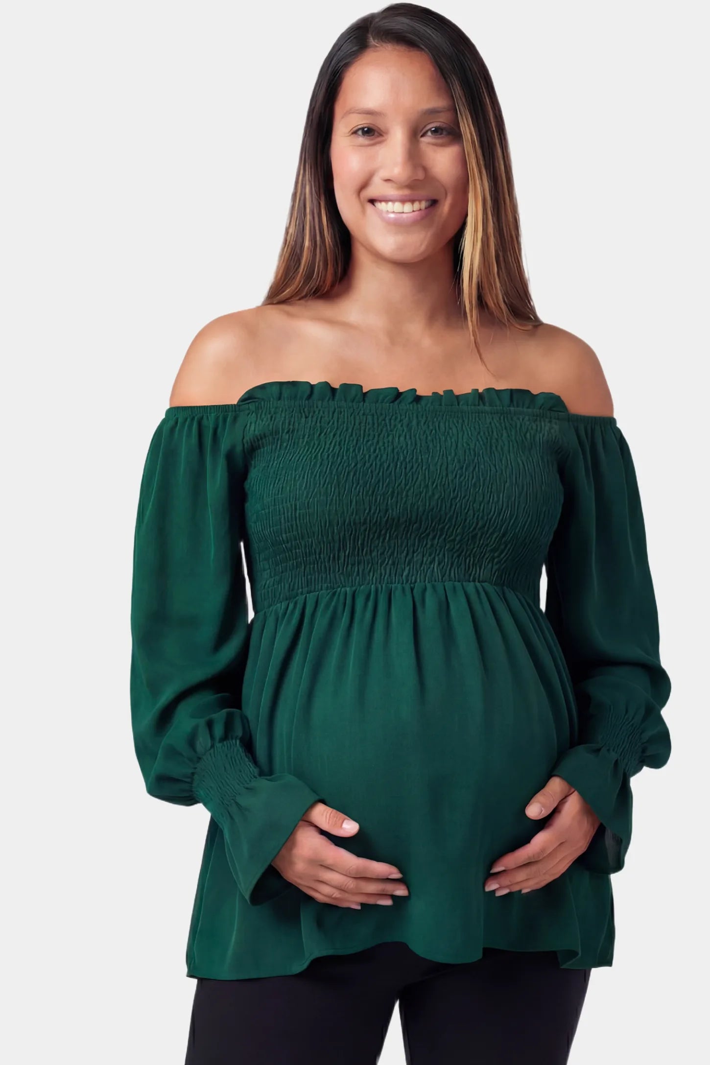 Smocked lantern sleeve maternity top in emerald green featuring off shoulder neckline in a front view on a pregnant model