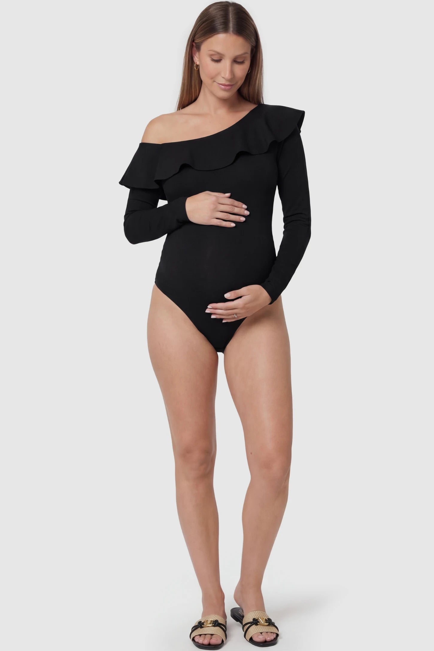 Off-shoulder ruffle trim maternity bodysuit in black with long-sleeve elegance, front view on pregnant model