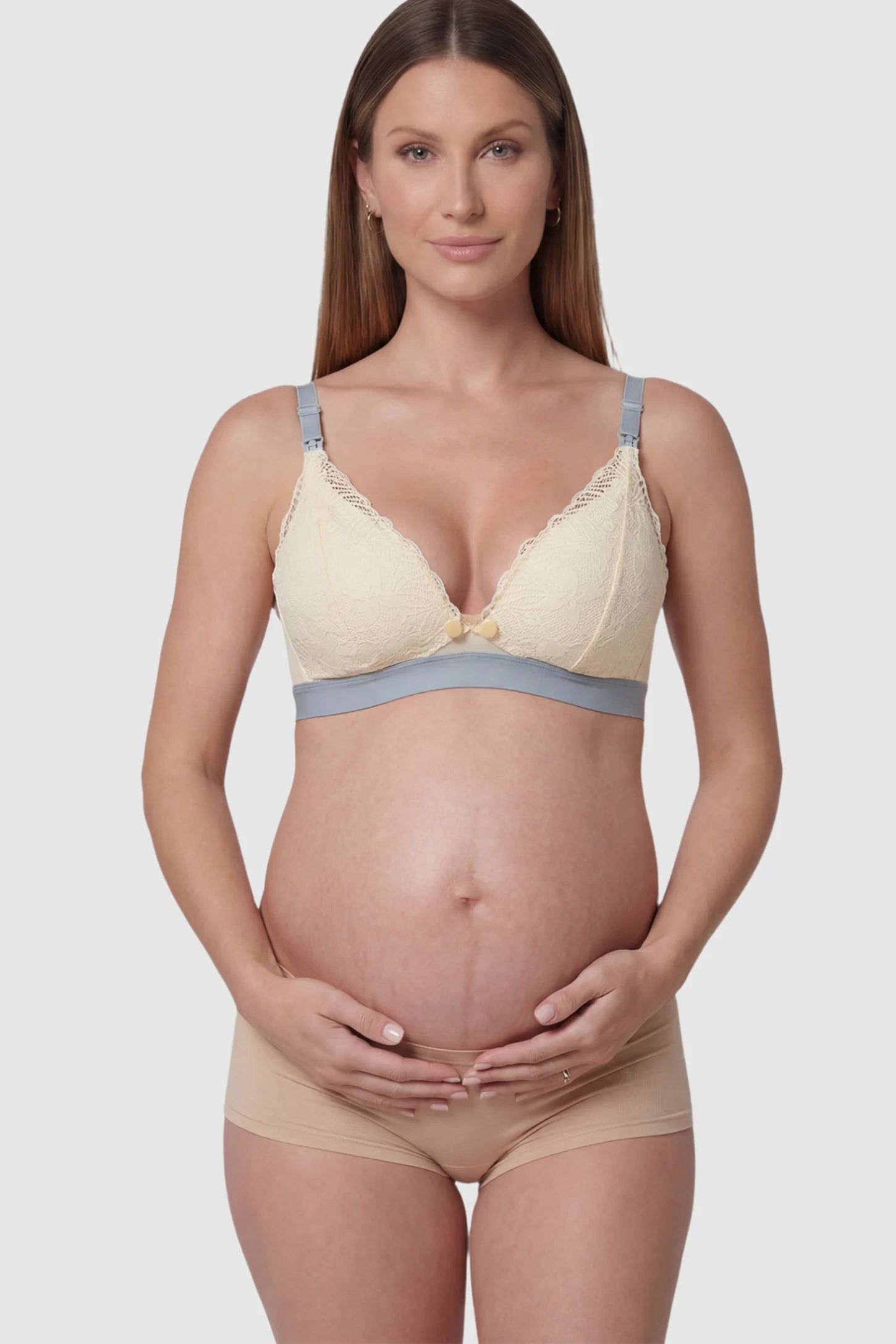 Floral Lace Front Button Maternity Nursing Bra in Skin featuring a wide grey elastic underband on a pregnant model.