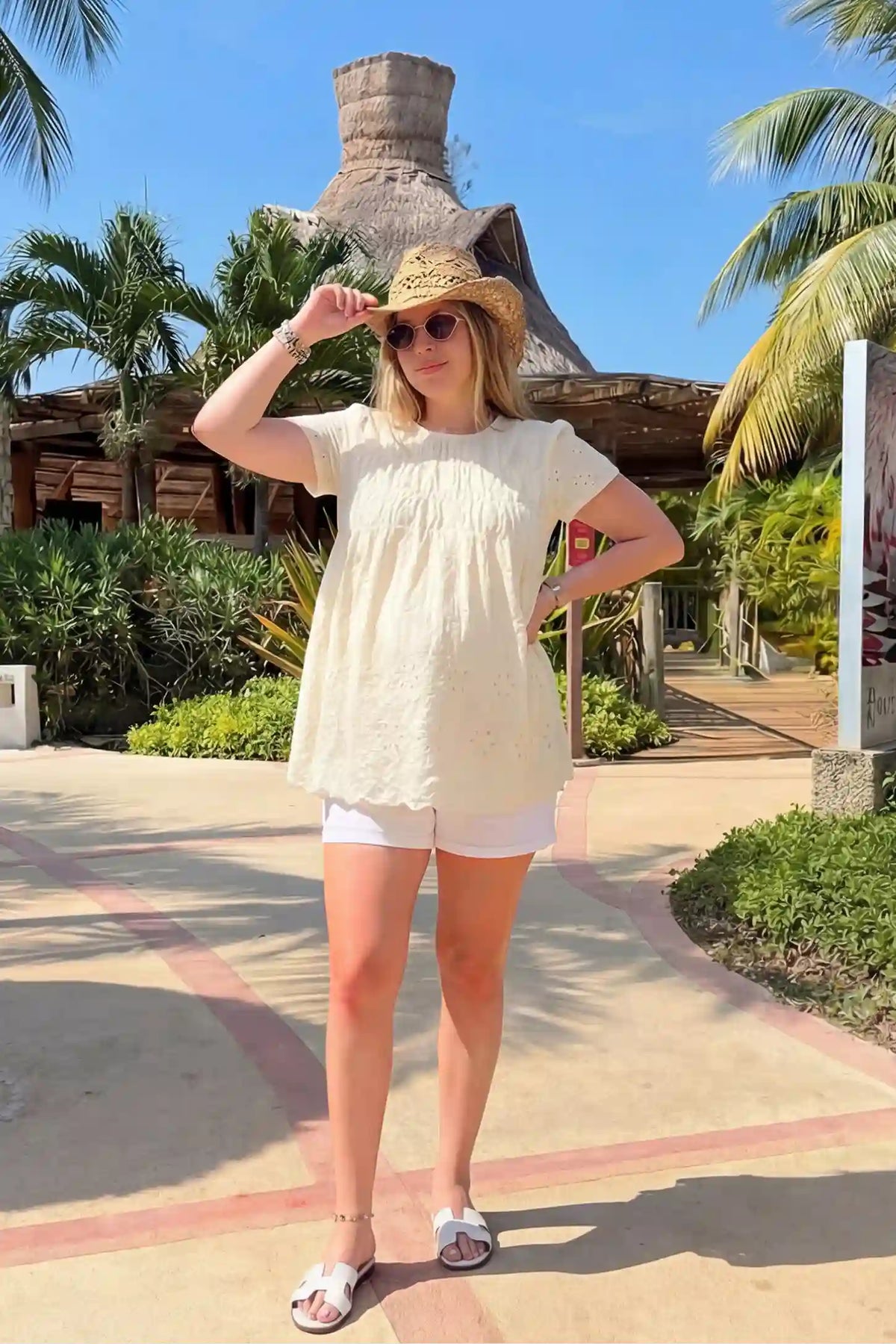 Floral eyelet round neck peplum maternity top in pale yellow with delicate floral eyelet detail, front view on pregnant model