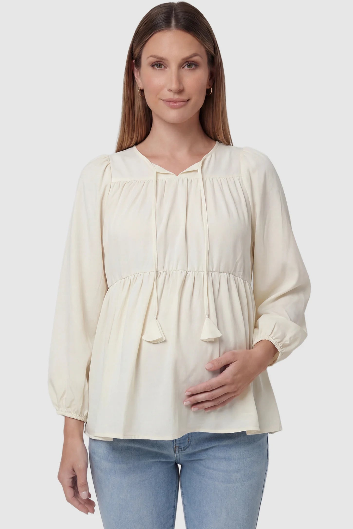 Tie-front tassel long sleeve peplum maternity blouse in pale yellow with tie-front tassel detail, front view on pregnant model