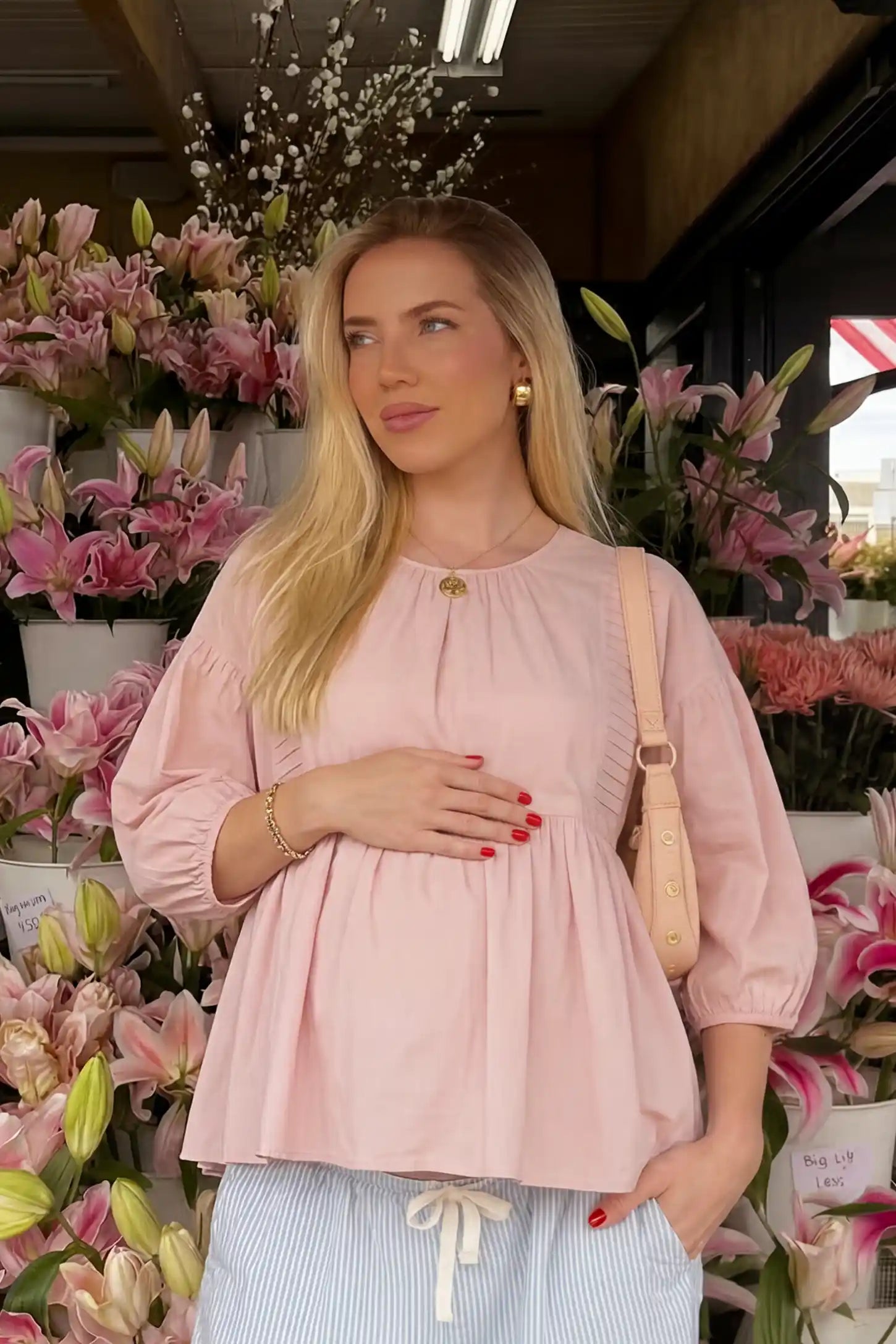 Peplum round neck maternity blouse in pink with flowy peplum and 3/4 sleeves, front view on pregnant model