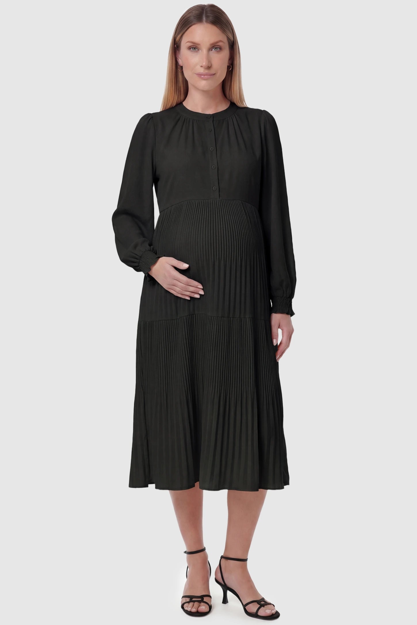 Button-up neck pleated tiered maternity midi dress in black with button-up neckline detail, front view on pregnant model