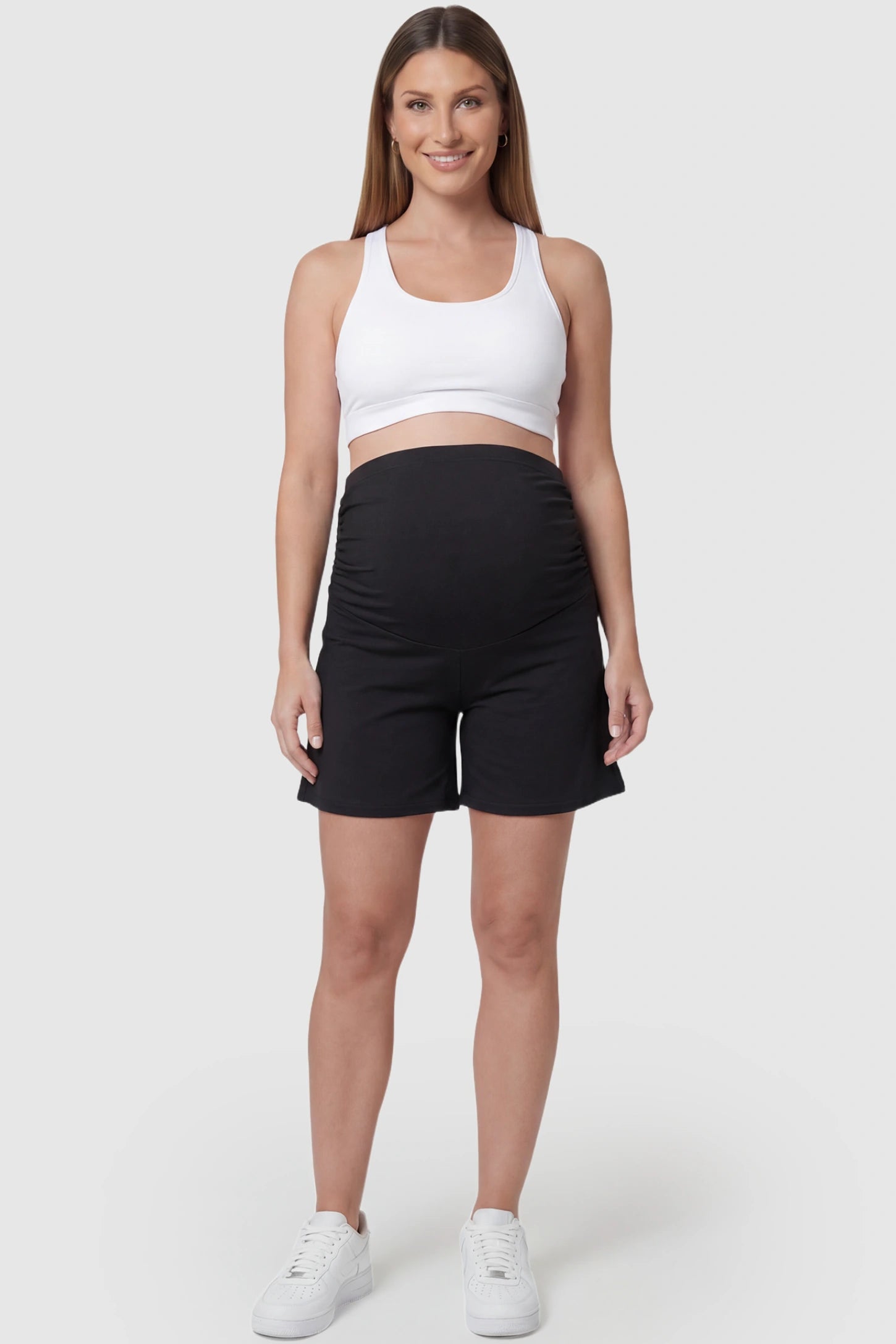 Full Panel Relaxed-Fit Maternity Shorts in black featuring seamless belly band and mid-thigh length on pregnant model front view.