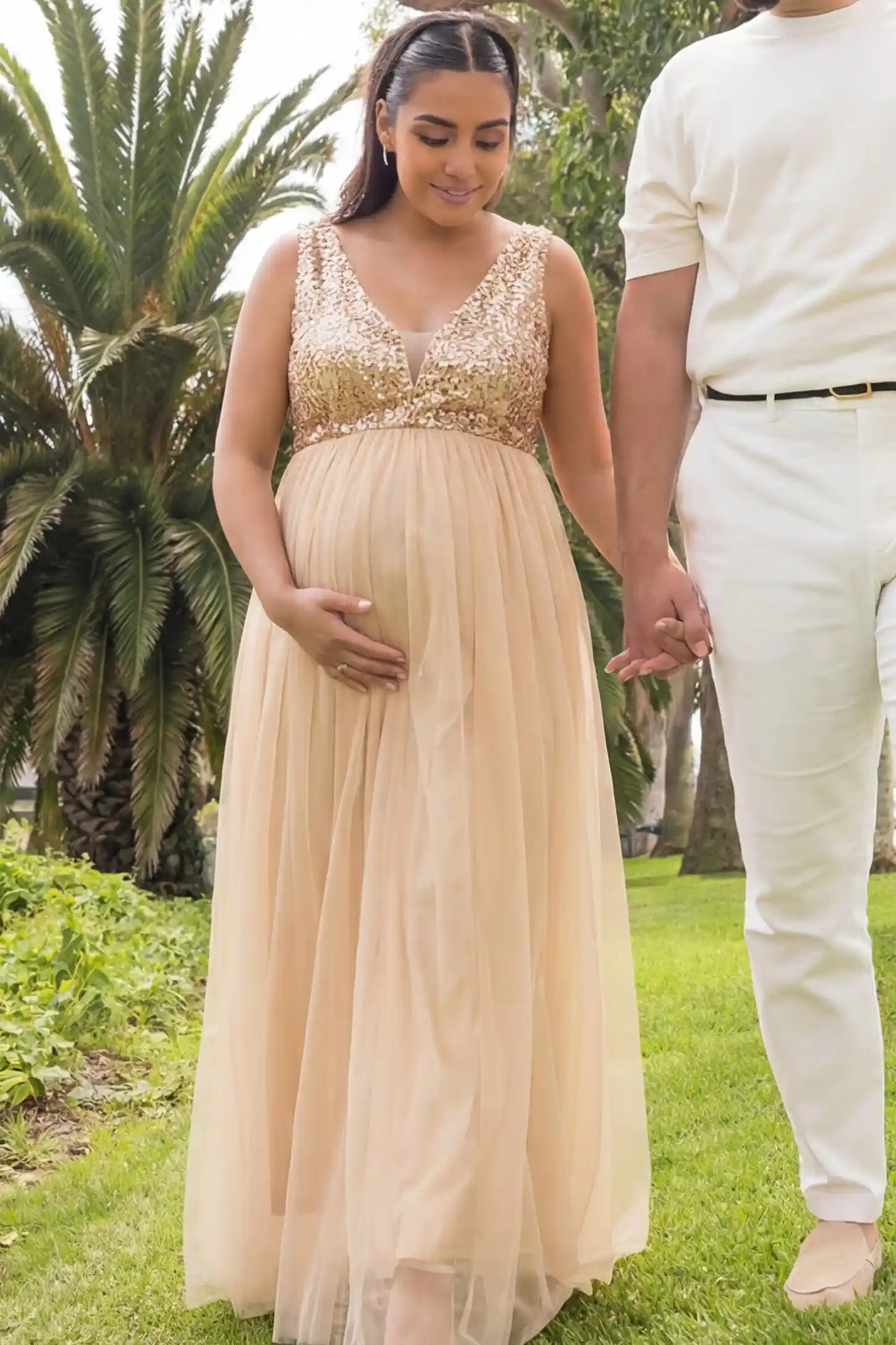 Sequin bodice sleeveless maxi maternity dress in gold featuring mesh skirt shown in full body front view on a editorial lifestyle model