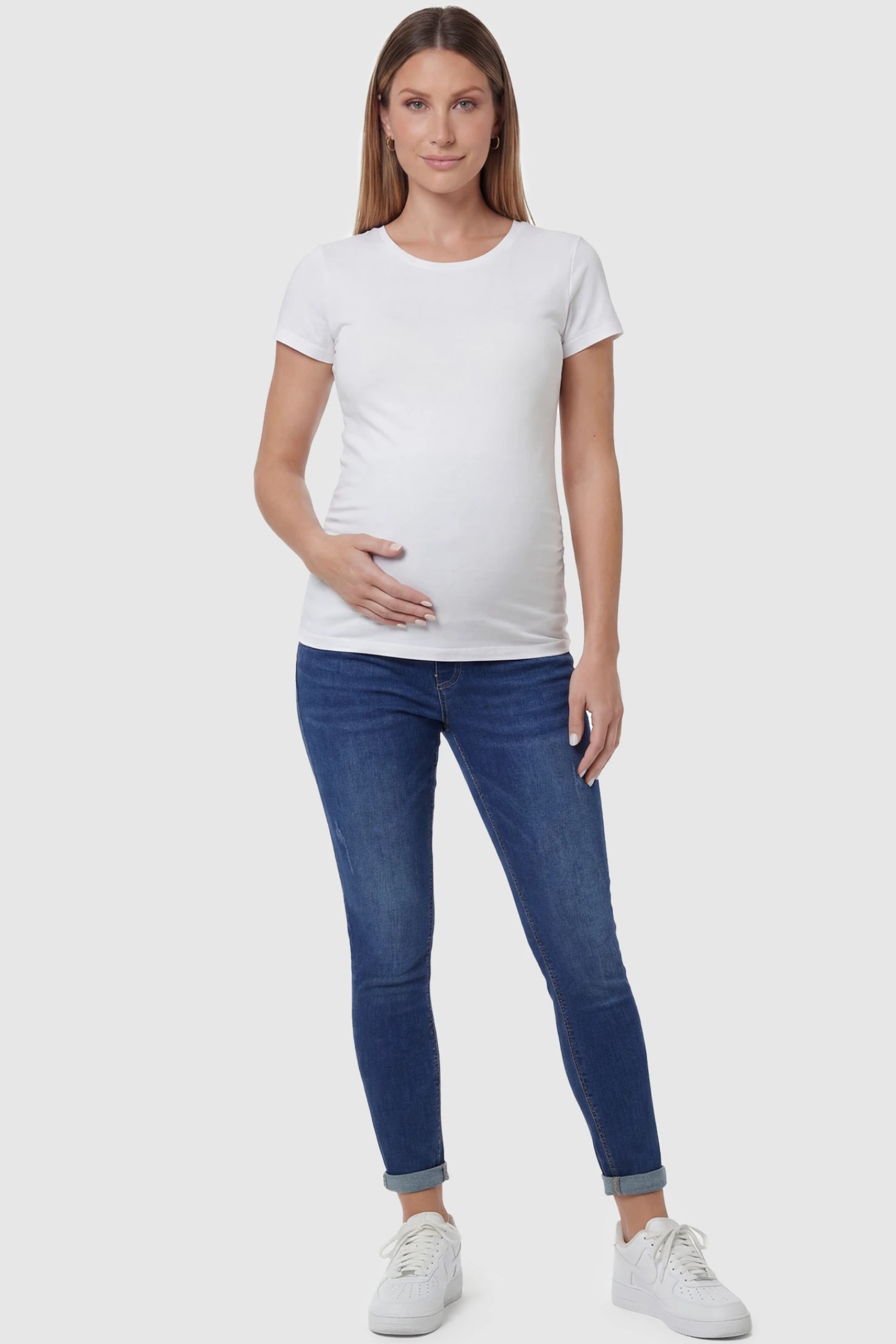 Cuffed Hem Skinny Maternity Jeans in dark blue featuring full belly panel and ankle-length cuffed hem on front view pregnant model.