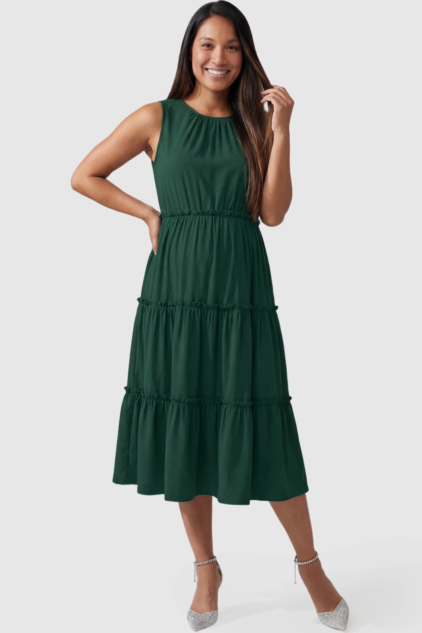 Solid Sleeveless Ruffle Tiered Maternity Midi Dress in dark green featuring a ruffle tiered skirt on a pregnant model posing front.