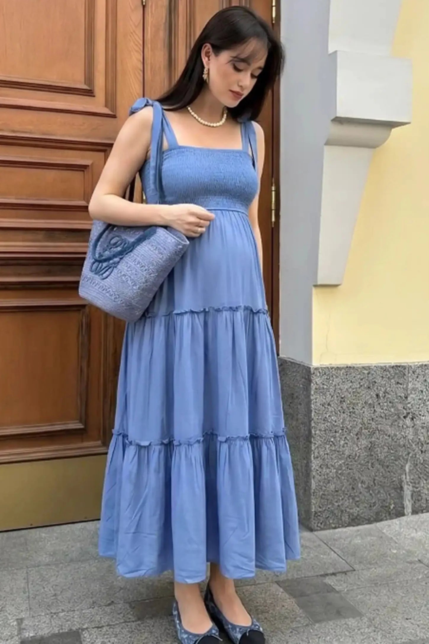 Smocked square neck tiered maternity midi dress in blue with square neckline, smocked bodice, and adjustable tie straps, editorial lifestyle view