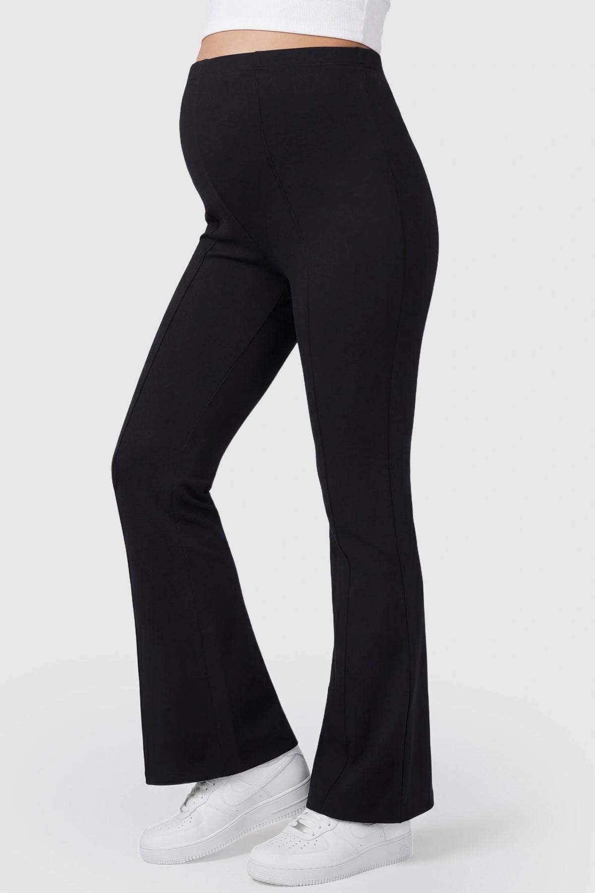 Buttery Soft High Waisted Flare Leg Maternity Pants in black featuring a visually lengthening flare leg on a pregnant model, side view.