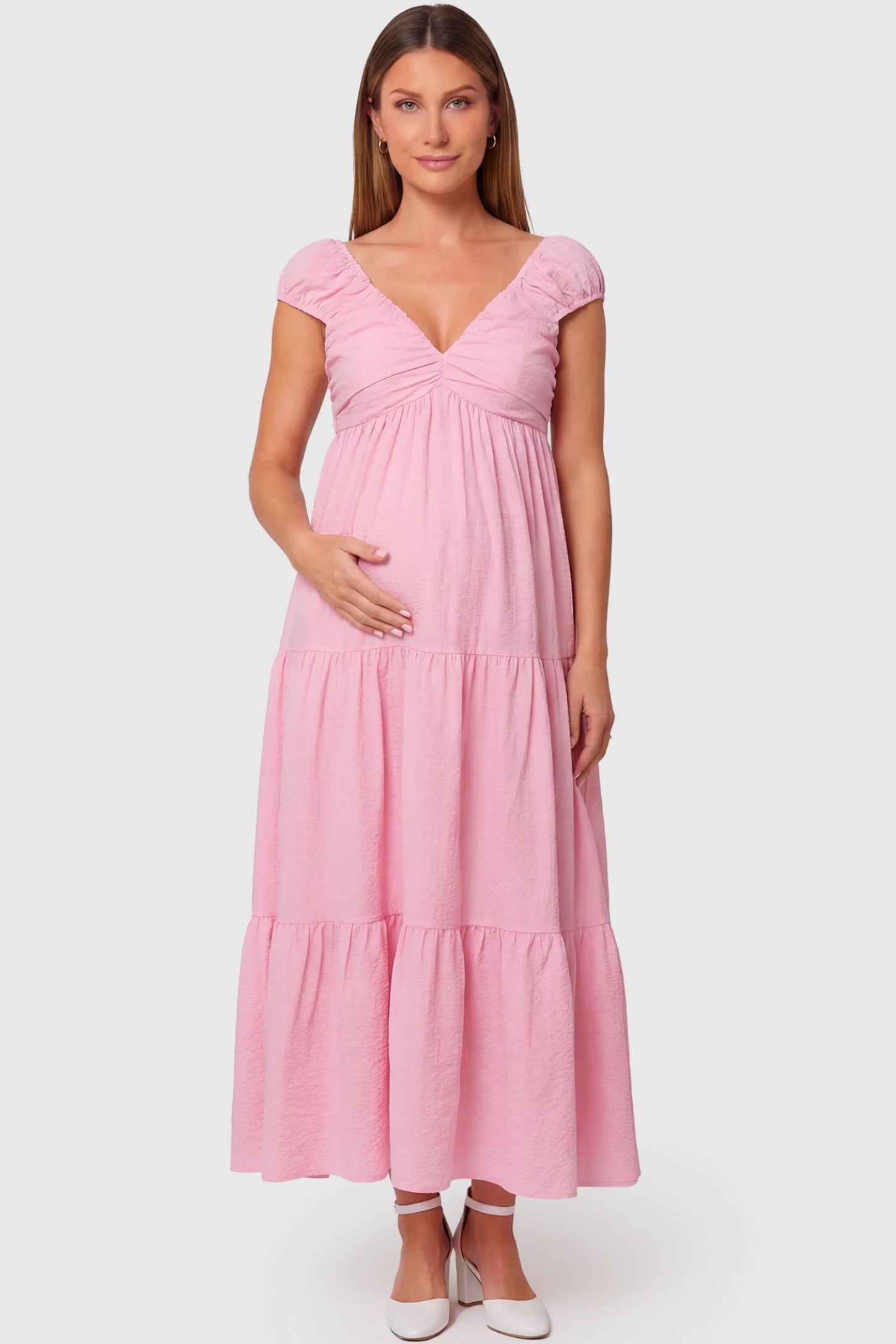 Short Puff Sleeve Tiered Maternity Maxi Dress in pink featuring a sweetheart V-neckline and empire waist on a pregnant model.