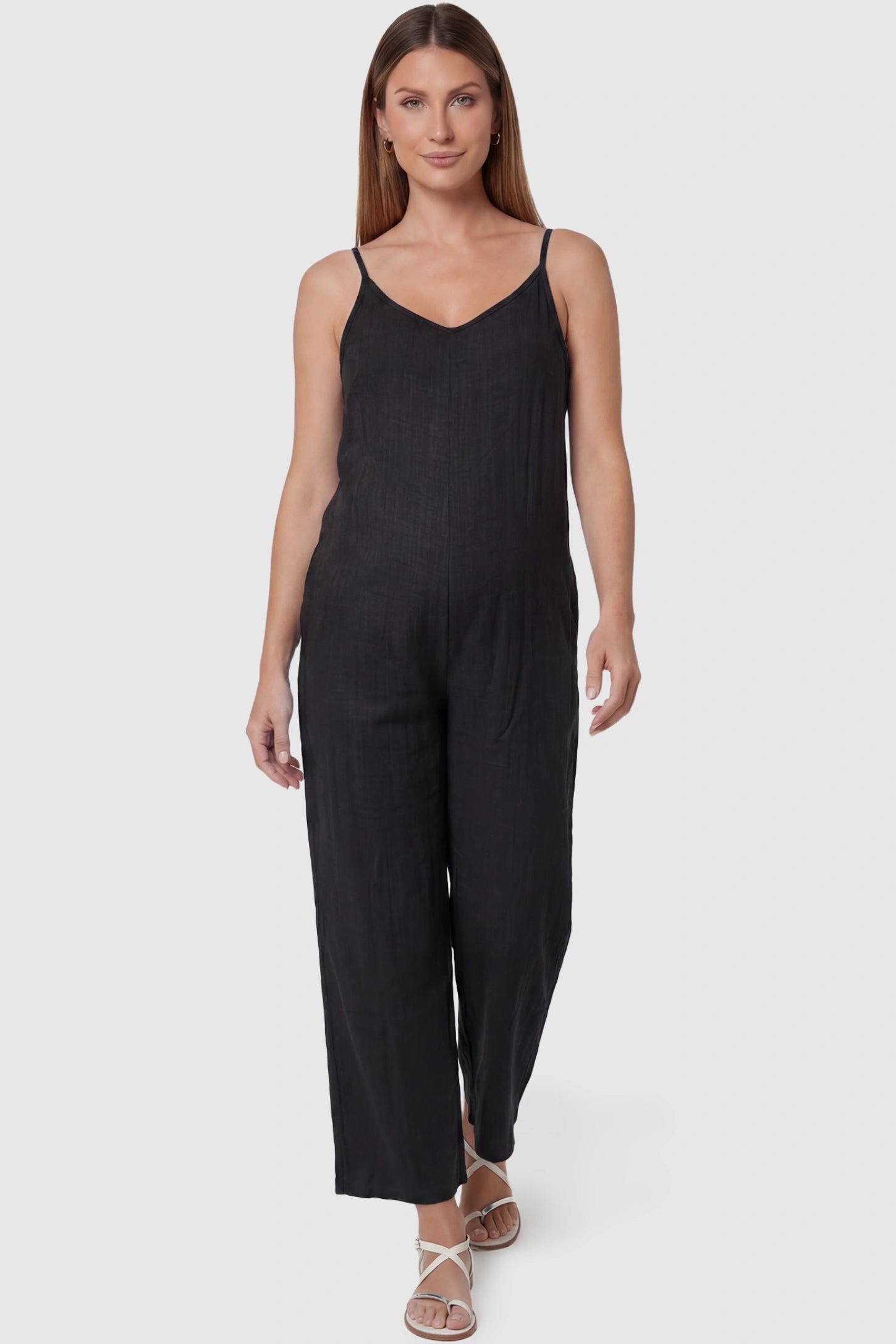 Wide-leg scoop neck pocketed maternity jumpsuit in black with sleeveless design, thin strap, and wide-leg silhouette, front view on pregnant model