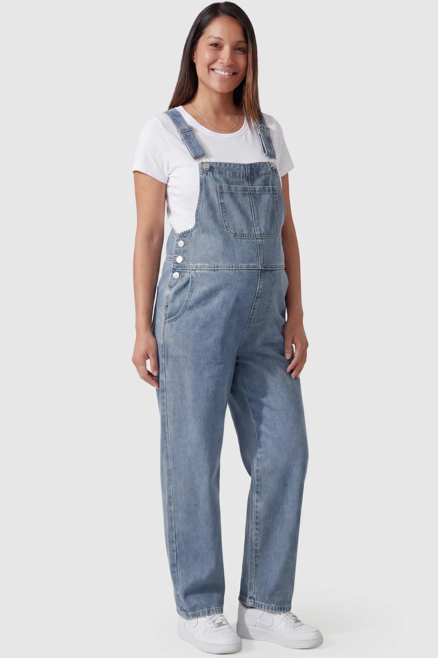 Wide leg relaxed fit maternity overalls in light blue with adjustable straps and front pockets, front view on pregnant model