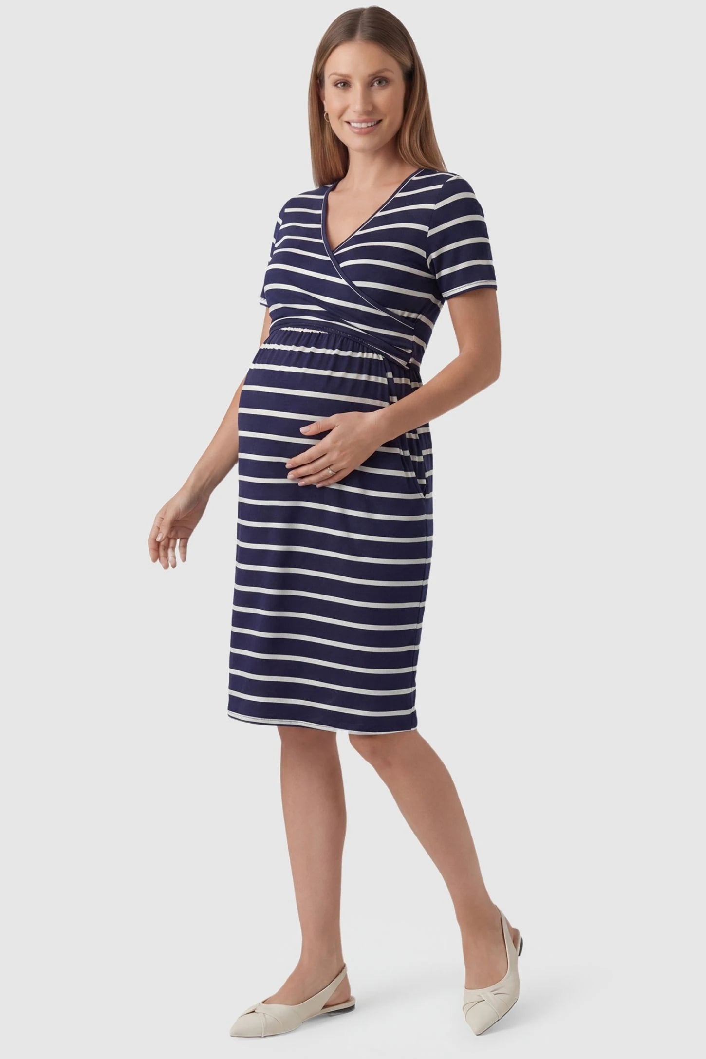 Short Sleeve Faux Wrap Maternity & Nursing Midi Dress in navy striped print featuring V-neck faux wrap bodice and empire waist on a pregnant model front view.