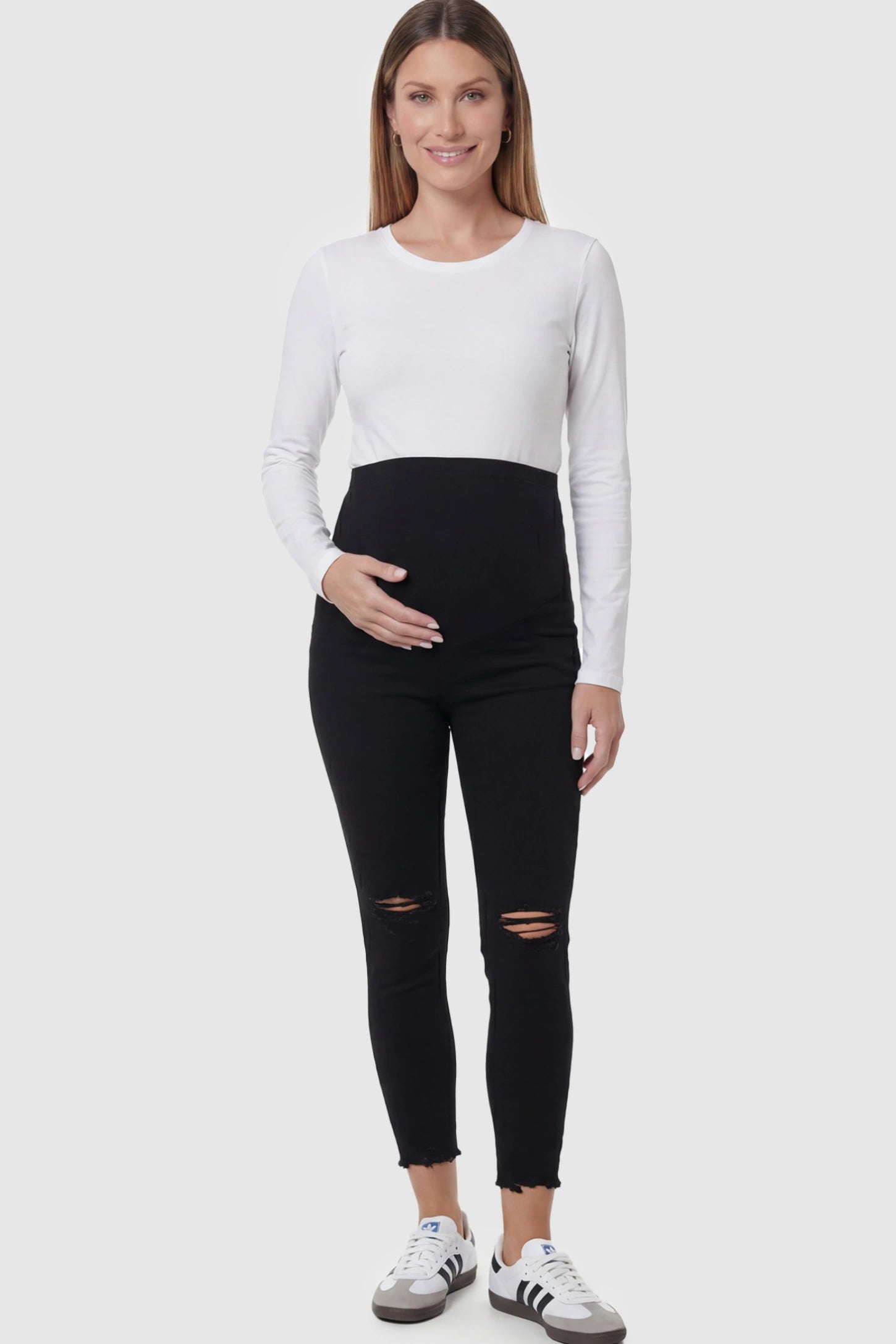 Stretch Panel Distressed Skinny Maternity Jeans in Black featuring a high-rise elastic waistband and ripped knees on a pregnant model.