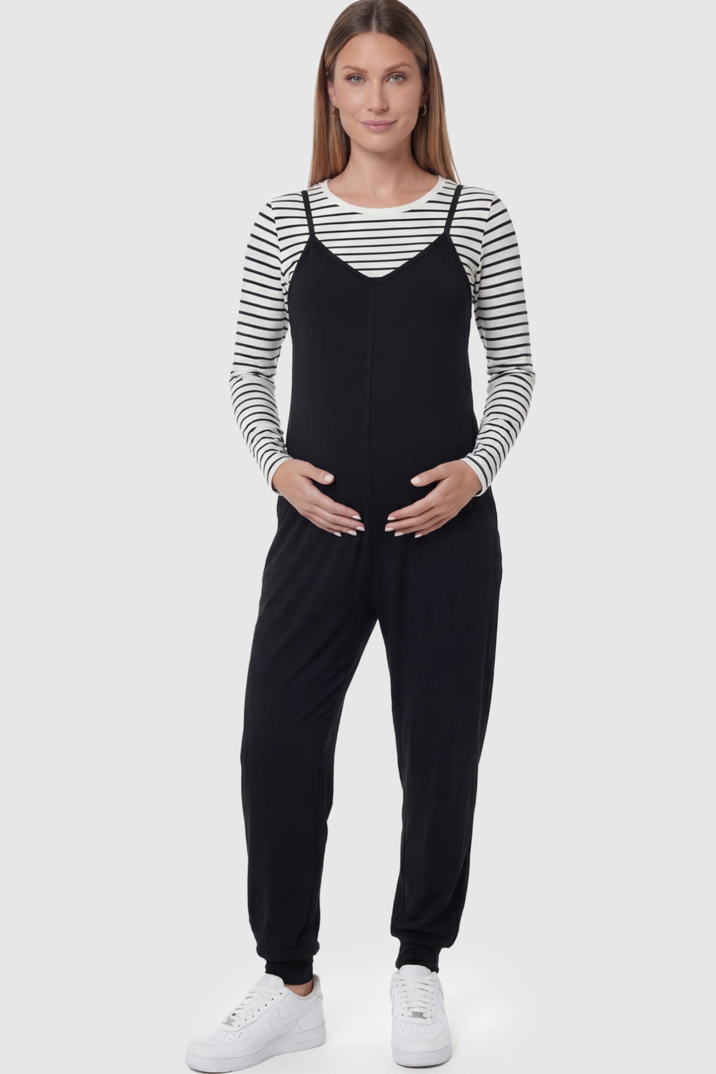 V-Neck Pocketed Maternity Jogger Jumpsuit in Black featuring cotton-spandex jersey and side pockets on a pregnant model.