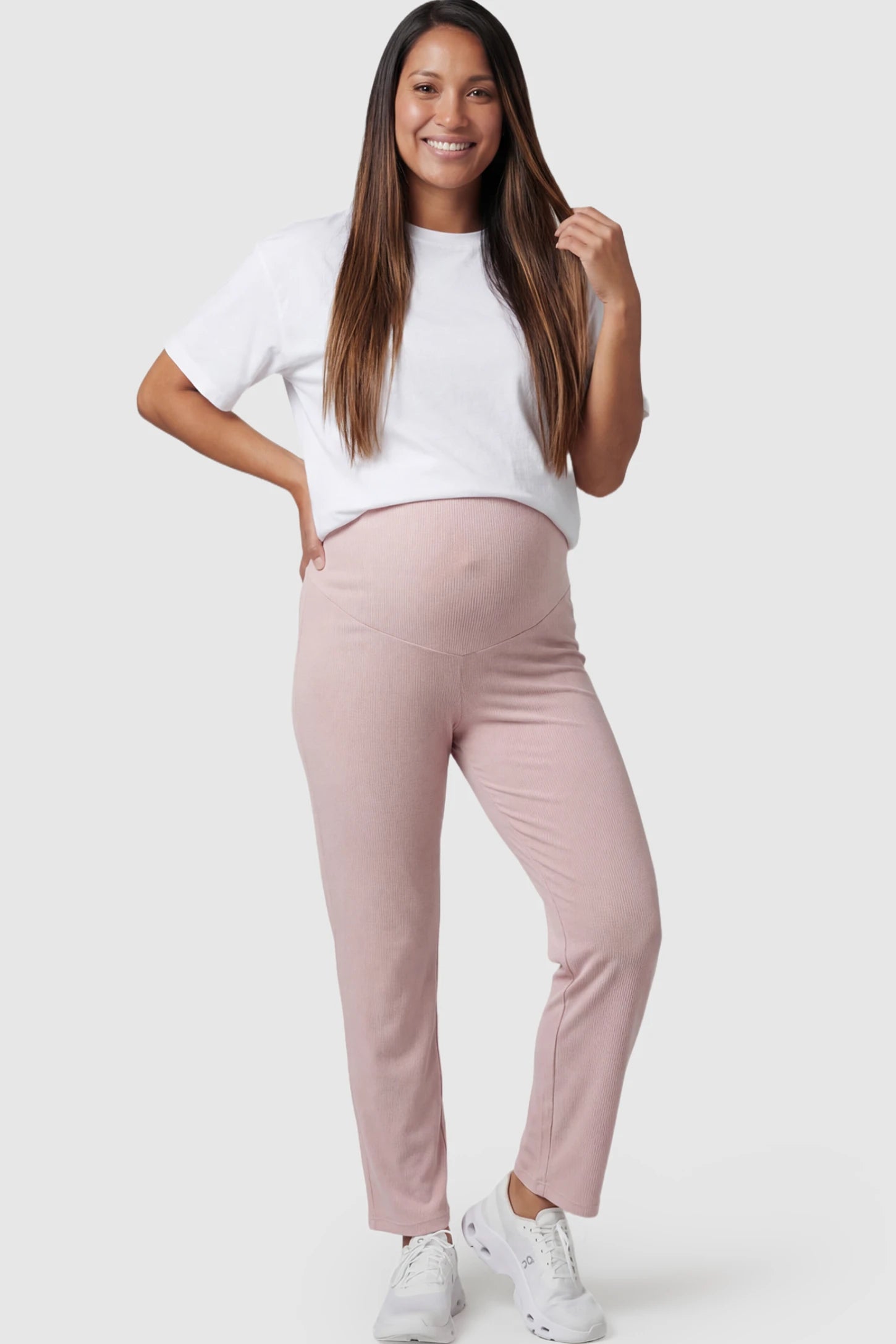 Straight Leg Maternity Pants in pink featuring an adjustable elastic waist on a pregnant model posing front.