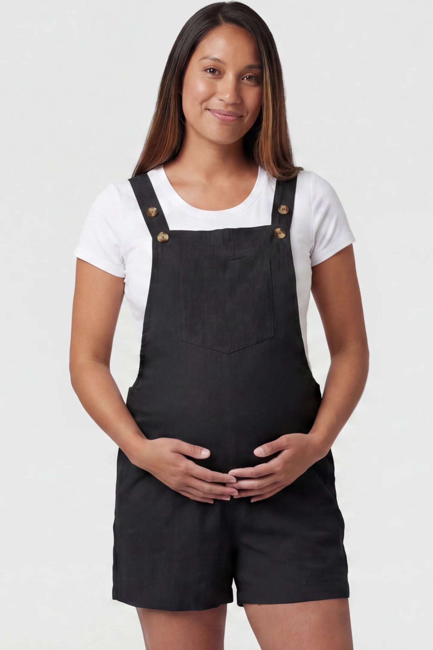 Adjustable Waist Pocketed Maternity Short Overalls in Black featuring a bib pocket on a pregnant model, front view.