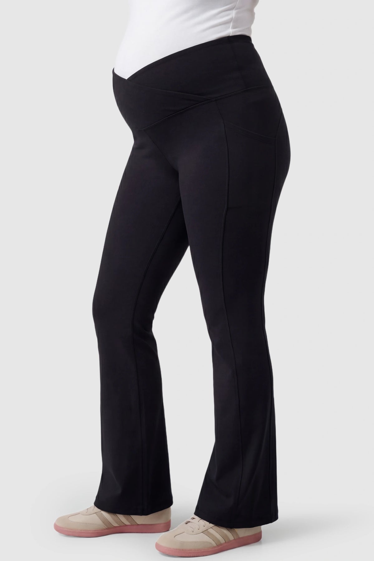 Crossover Waistline Flared Maternity Pants in Black featuring a V-shaped band on a pregnant model, side view.