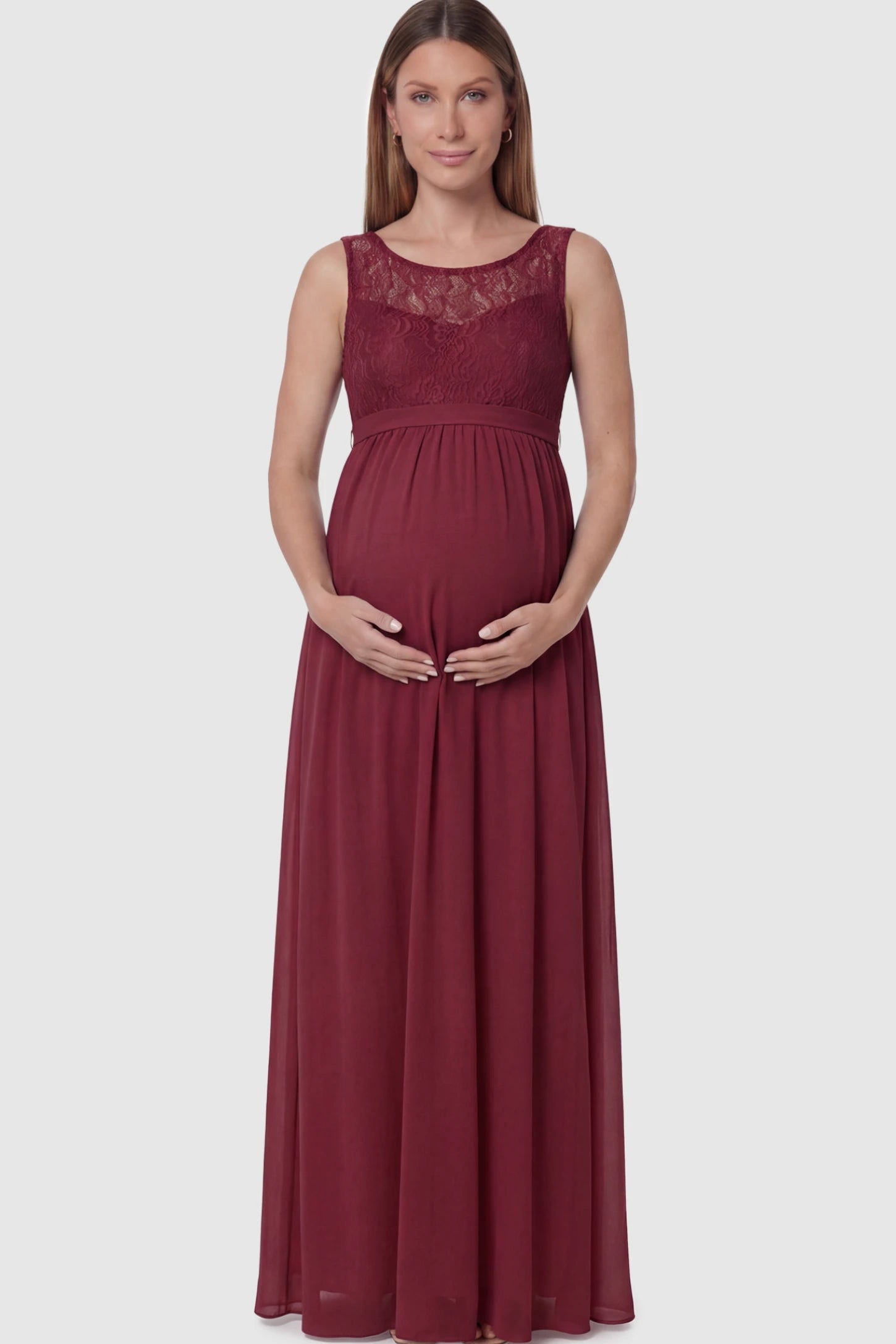 Floral Lace Sleeveless Maternity Maxi Dress in Burgundy featuring a flowing skirt on a pregnant model posing front.