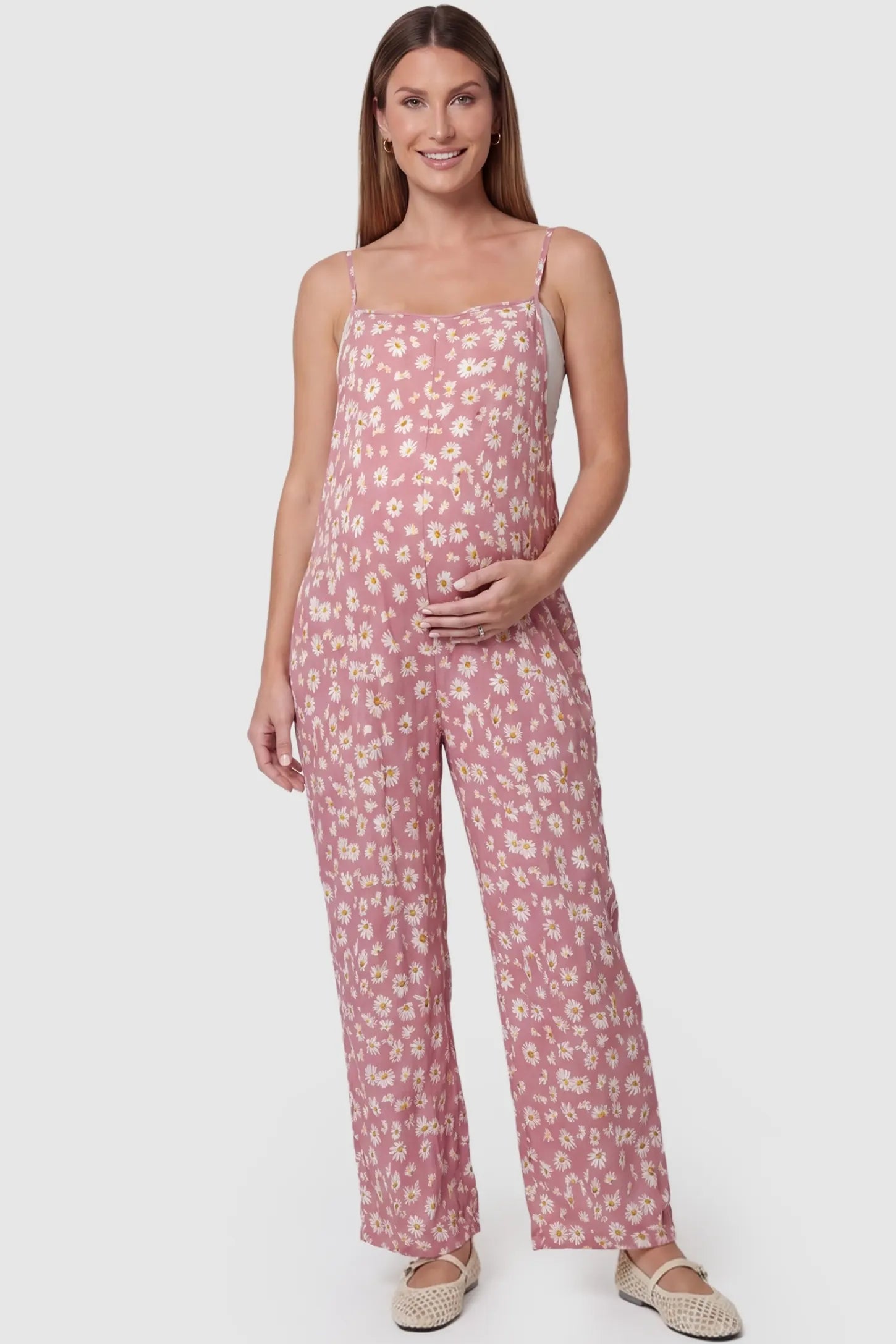 Floral Wide-Leg Pocket Jumpsuit in Pink featuring an all-over daisy print on a pregnant model, front view.