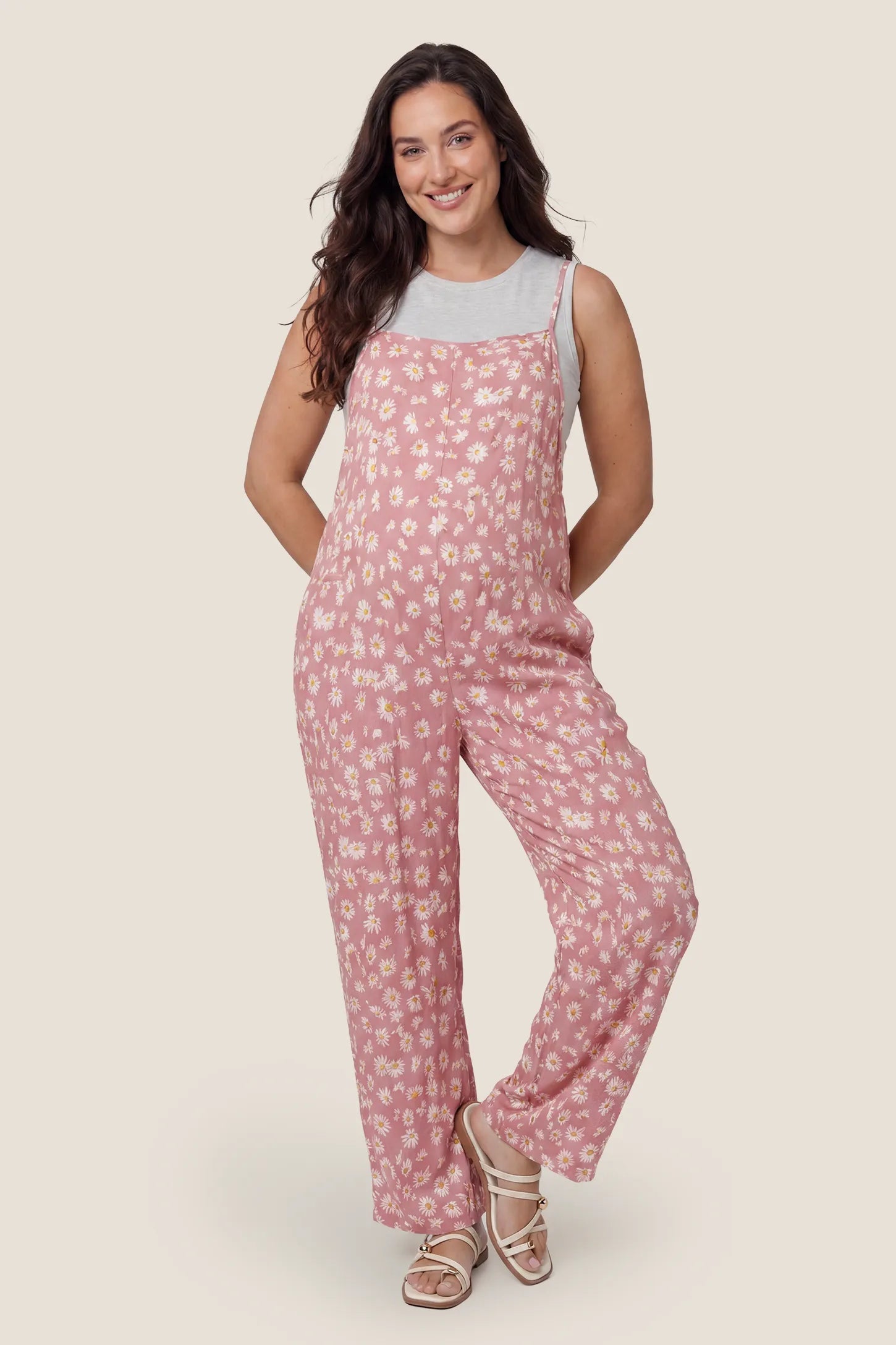 Floral Wide-Leg Pocket Jumpsuit in Pink featuring an all-over daisy print on a pregnant model, front view.