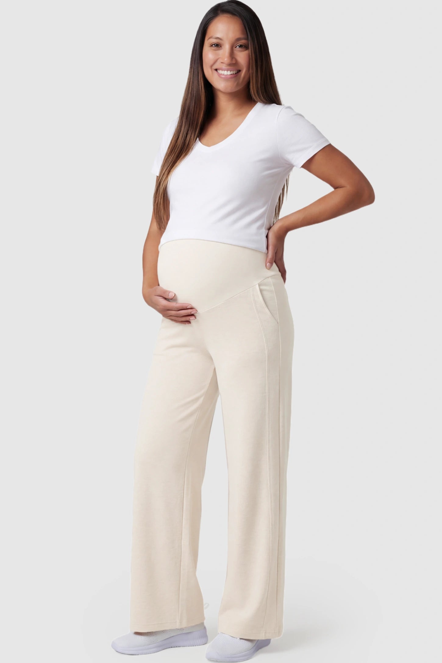 Full Panel Wide Leg Maternity Lounge Pants in beige featuring a high-stretch full belly panel and pockets on a pregnant model showing front.