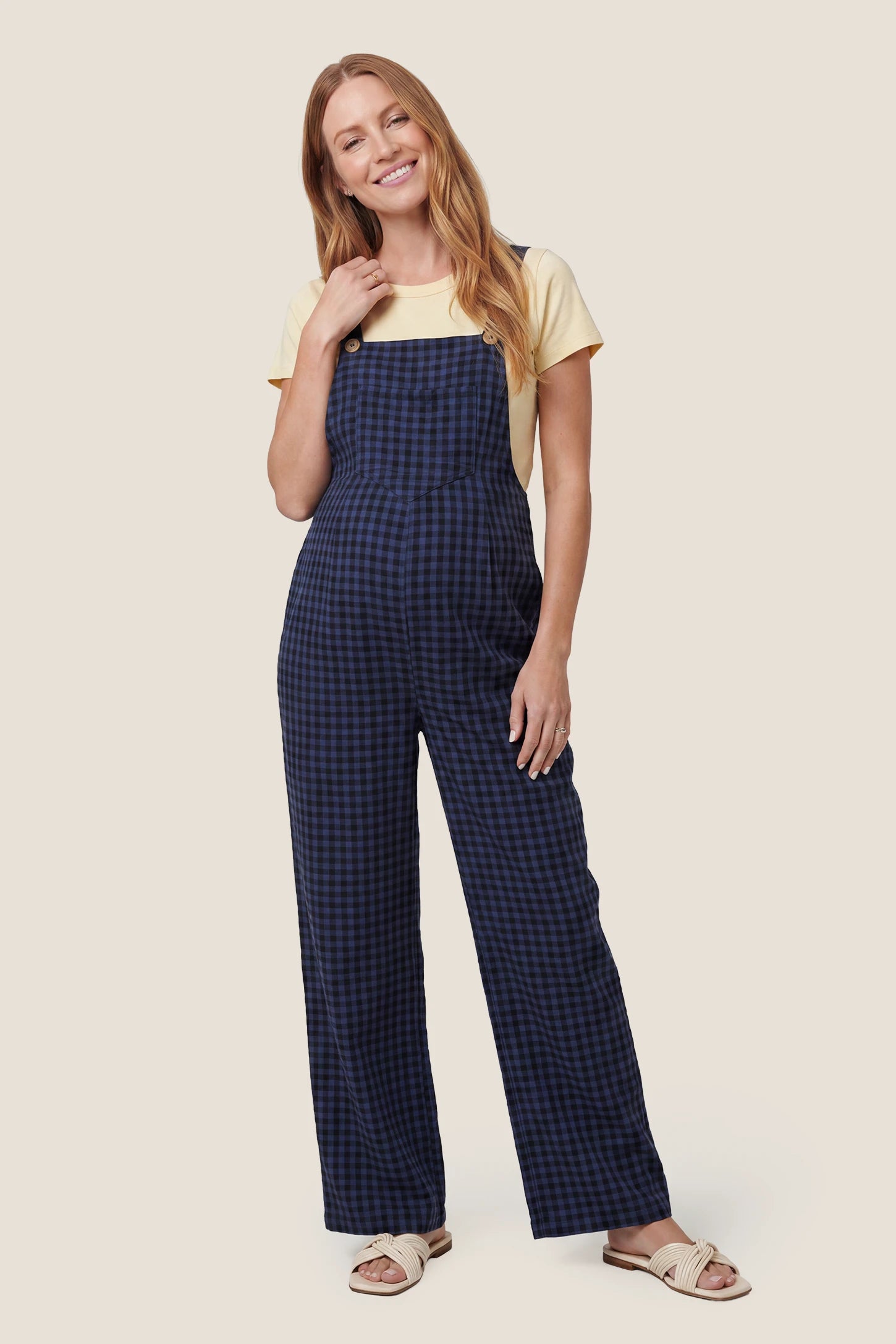Plaid Square-Neck Button-Detail Maternity Jumpsuit in Blue featuring a front pocket on a pregnant model in a front view.