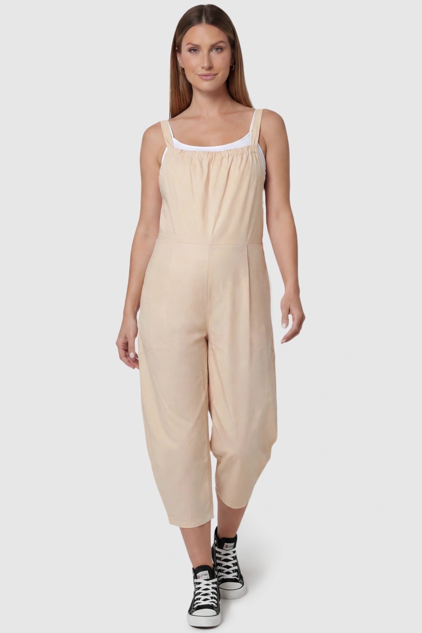Sleeveless Balloon-Leg Maternity Jumpsuit in Beige featuring deep side pockets on a pregnant model, front view.