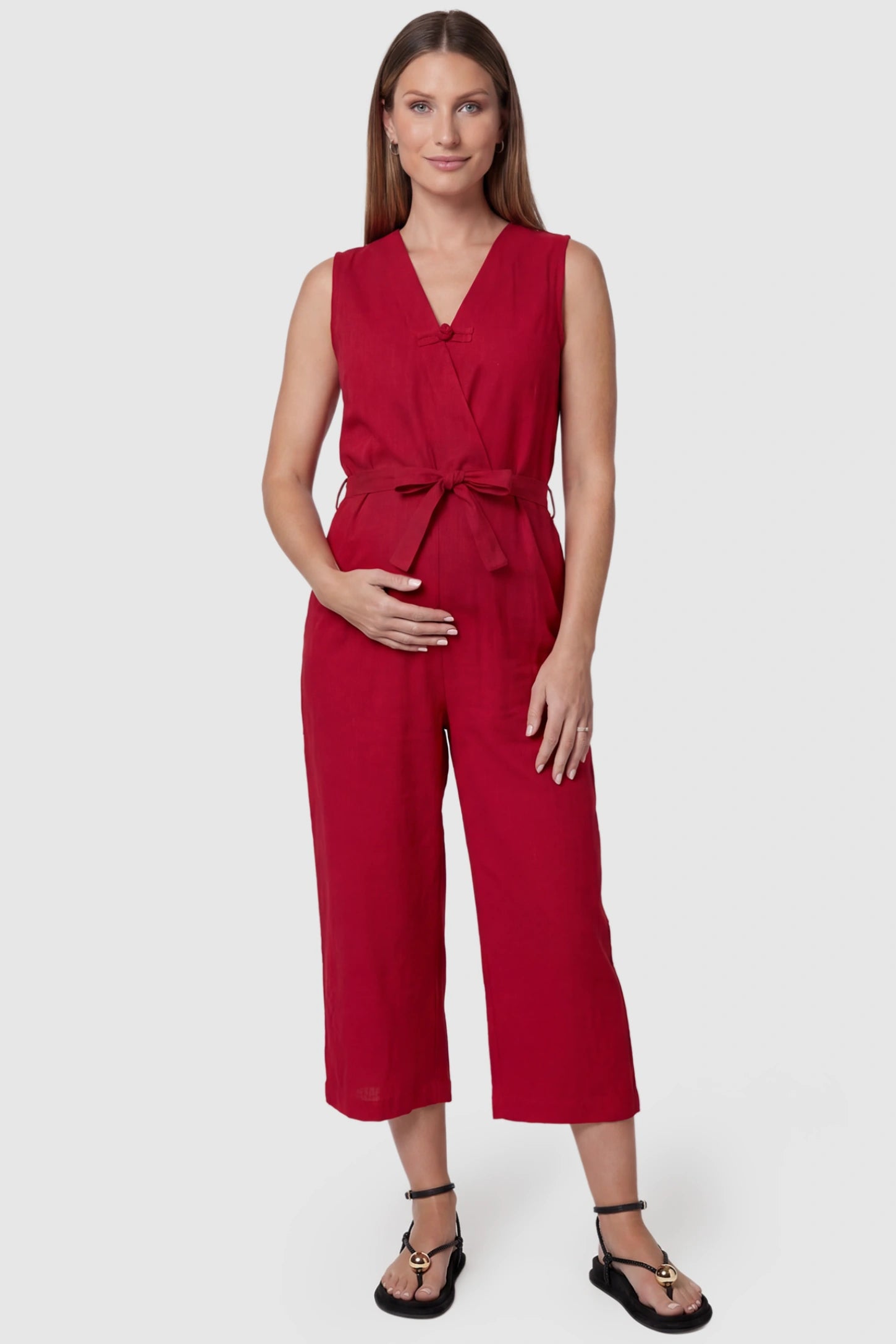 Sleeveless V-Neck Tie-Waist Maternity Jumpsuit in Red featuring a relaxed wide-leg design on a pregnant model, front view.