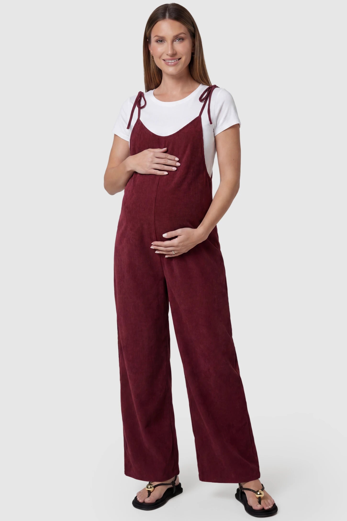 Solid Sleeveless Wide Leg Maternity Jumpsuit in Wine Red featuring a flowy silhouette on a pregnant model, front view.