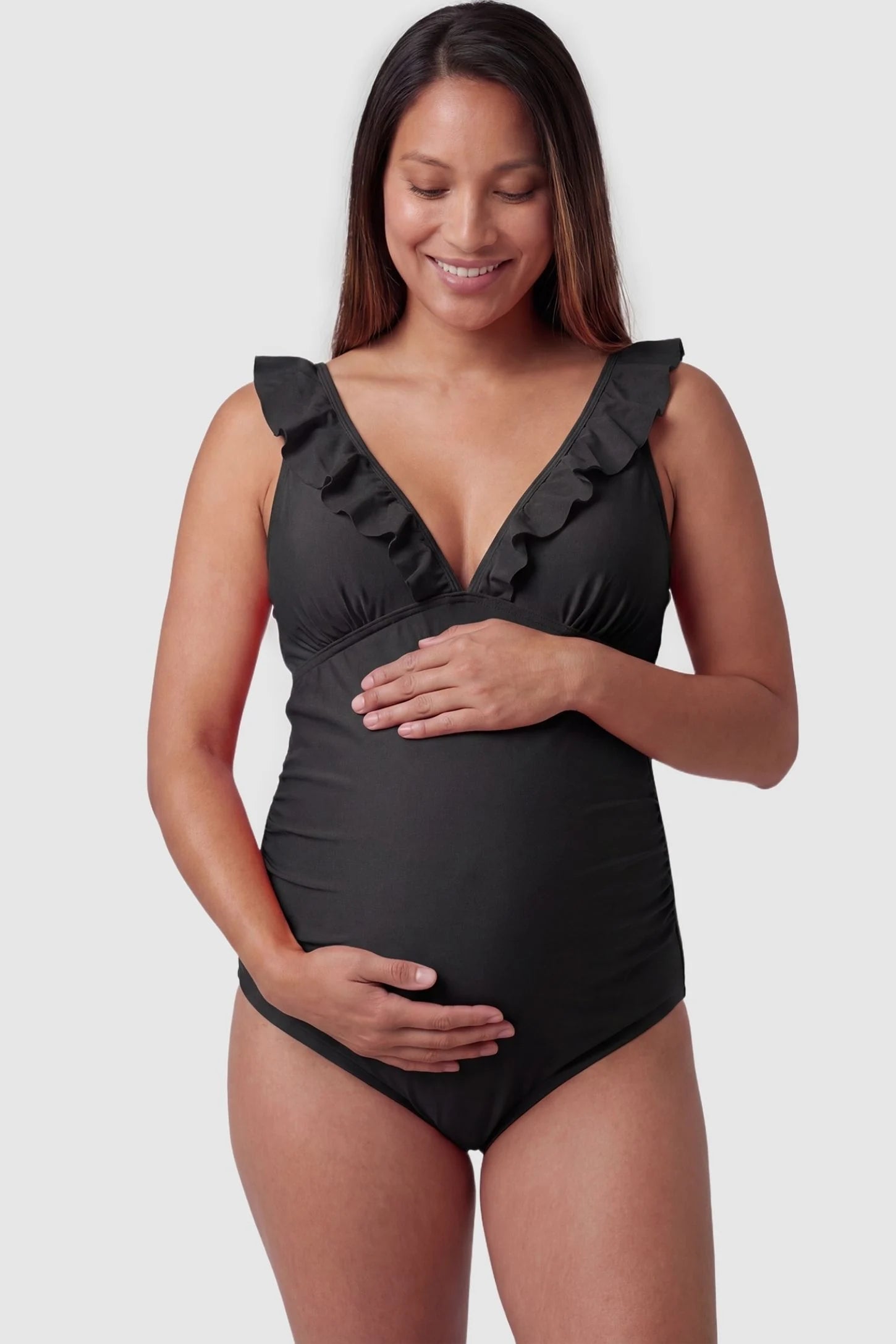 Smooth Matte Ruched Maternity One-Piece Swimsuit in Black featuring ruffle straps and a V-neck front on a pregnant model, front view.