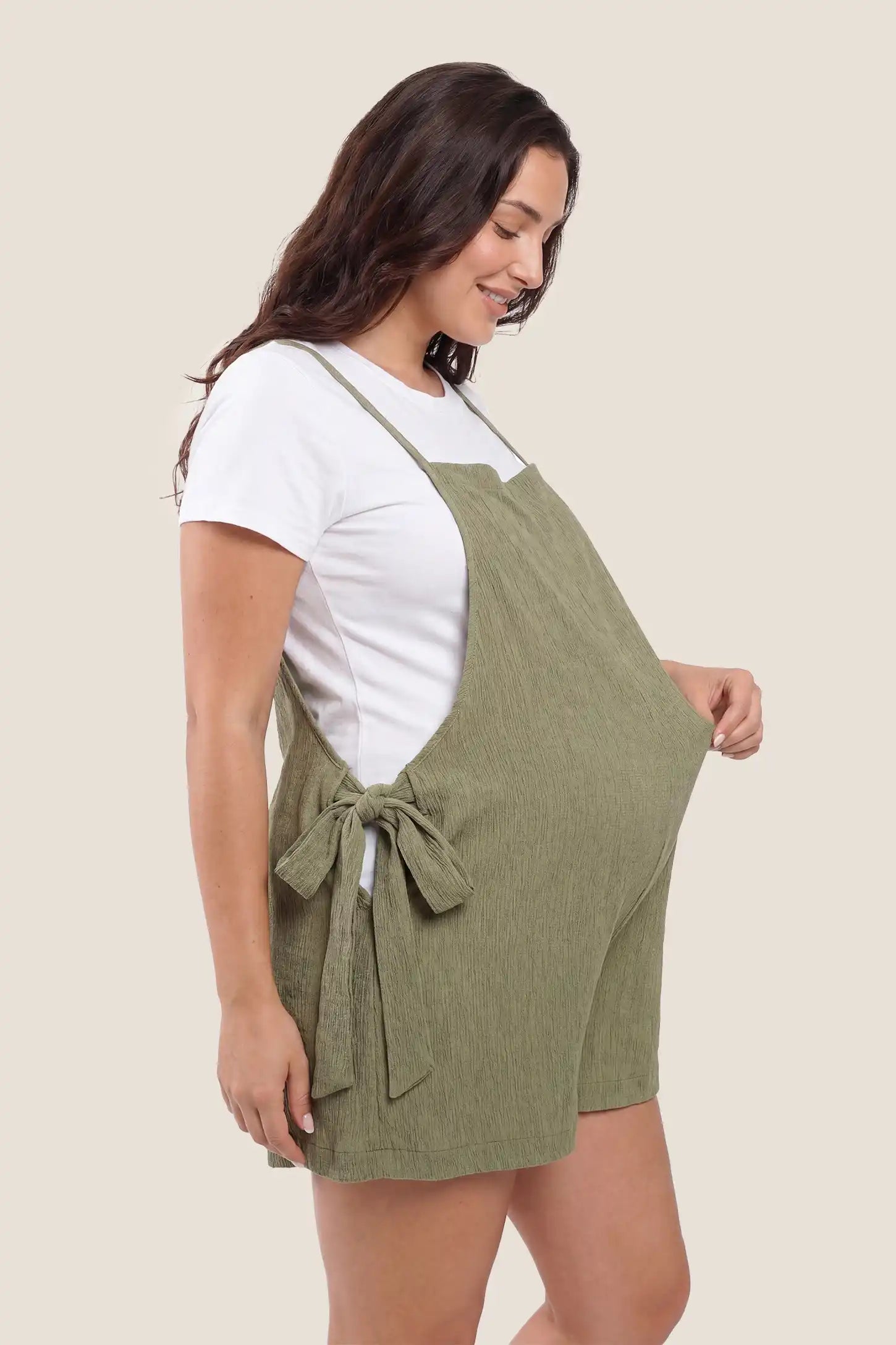 Side view of Green Spaghetti Strap Tie-Side Maternity Romper highlighting the adjustable side-tie closures on a pregnant model.