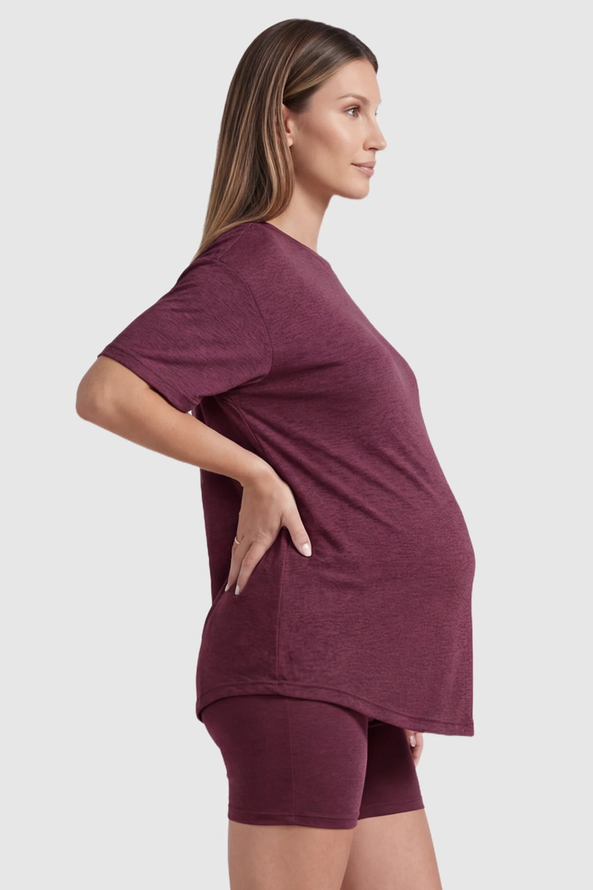 Stretch Oversized Tee & Biker Short Maternity Lounge Set in burgundy featuring a loose-fit tee and flexible waistband shorts on a pregnant model, side view.