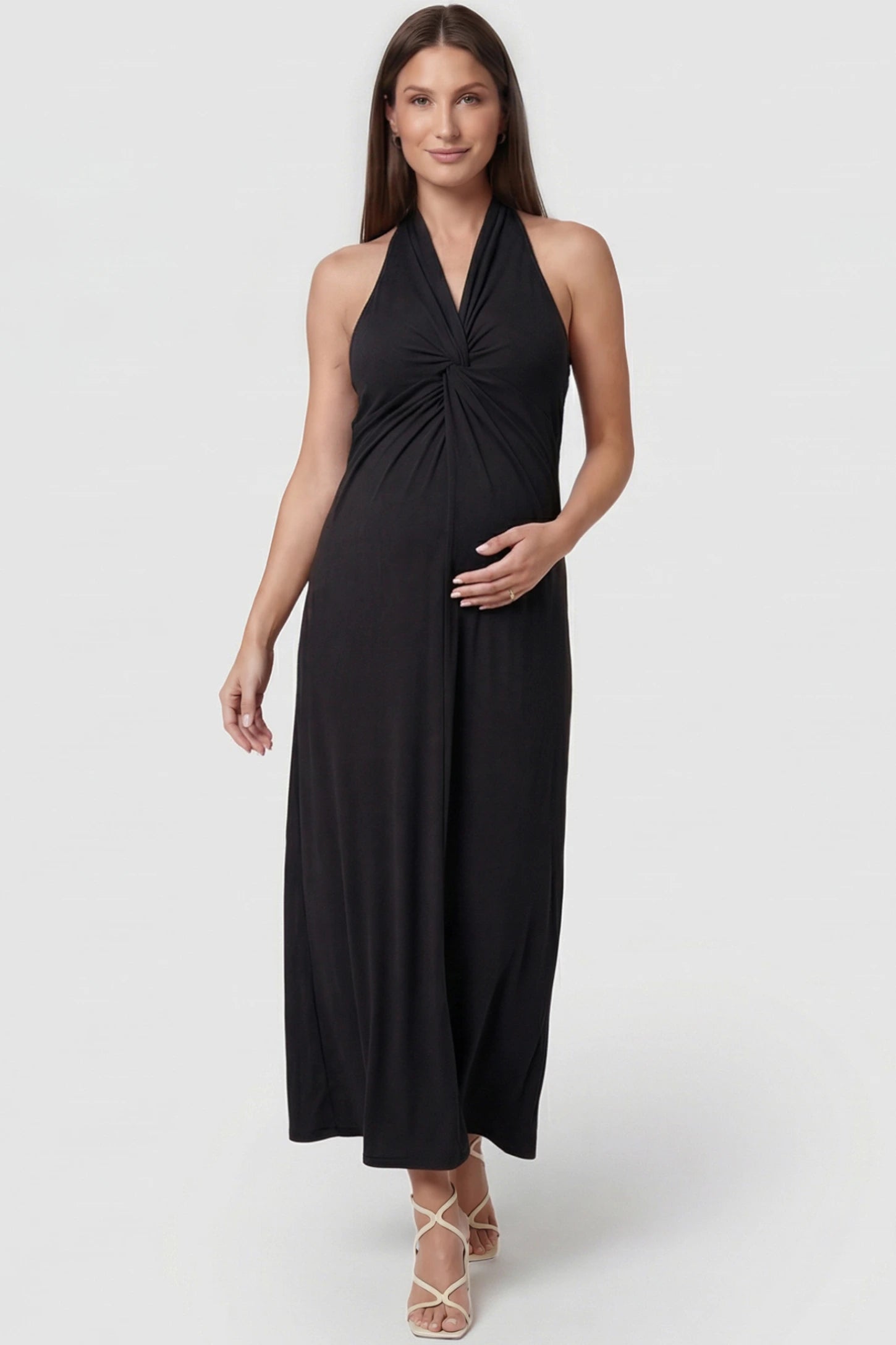 Twist Front Halter Neck Maternity Maxi Dress in Black featuring knot detail, sleeveless, A-line silhouette on a pregnant model, front view.