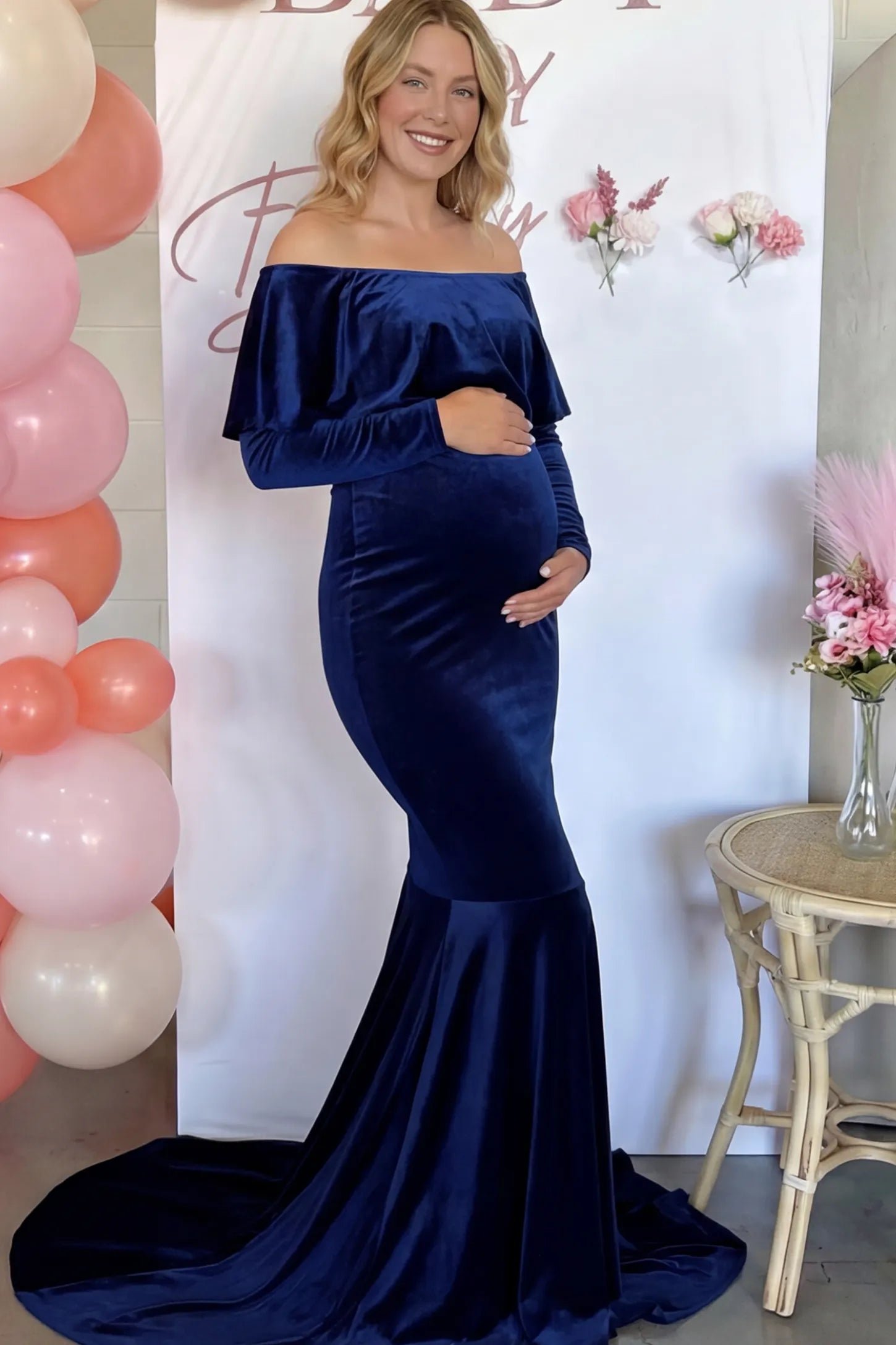 Velvet Off-the-Shoulder Maternity Mermaid Gown in Dark Blue featuring a ruffled neckline and long sleeves on a pregnant model.
