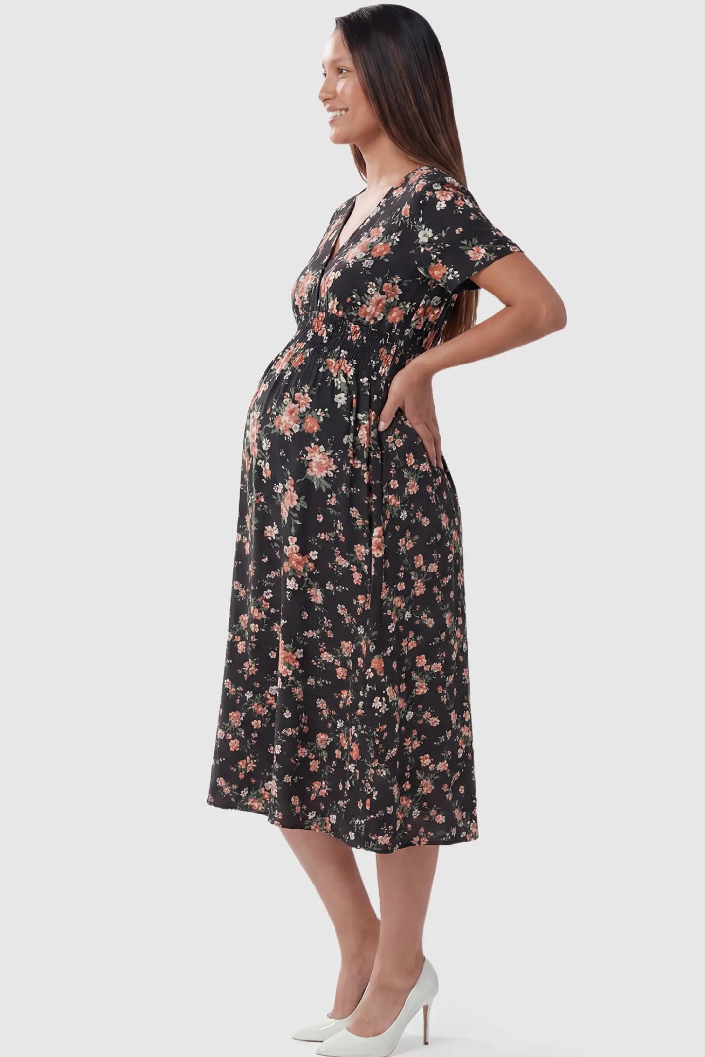 Smocked Waist Crossover Maternity Midi Dress Smocked Waist Crossover Maternity Midi Dress in black floral print featuring V-neck wrap bodice and A-line midi skirt on pregnant model.