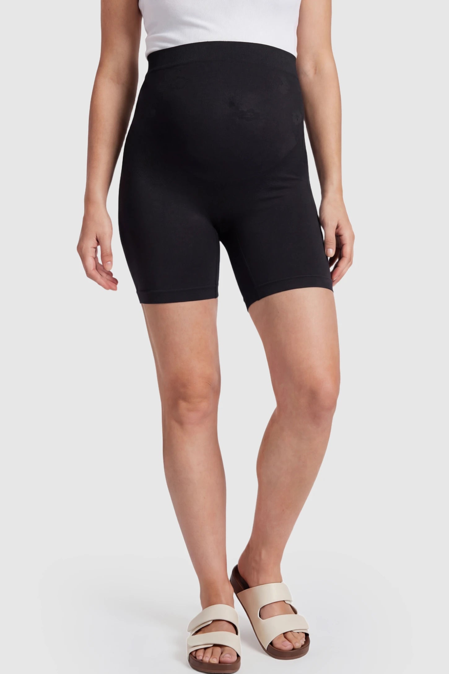 Seamless High Waisted Maternity Shapewear Shorts Seamless High-Waisted Mid Thigh Maternity Shapewear Shorts in Black featuring a smooth belly support panel on a pregnant model.