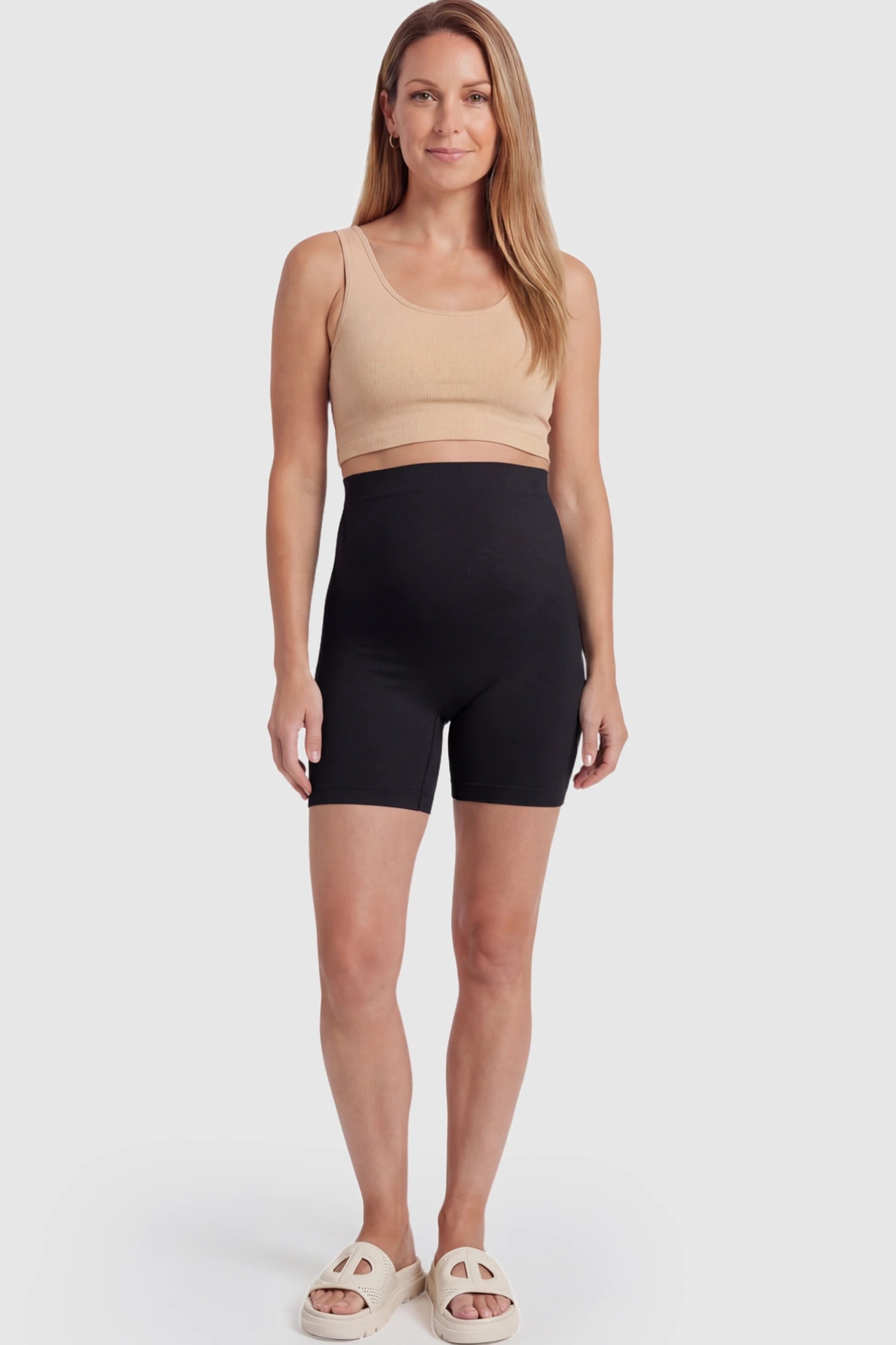 Seamless High Waisted Maternity Shapewear Shorts Seamless High-Waisted Mid Thigh Maternity Shapewear Shorts in Black featuring a smooth belly support panel on a postpartum model.